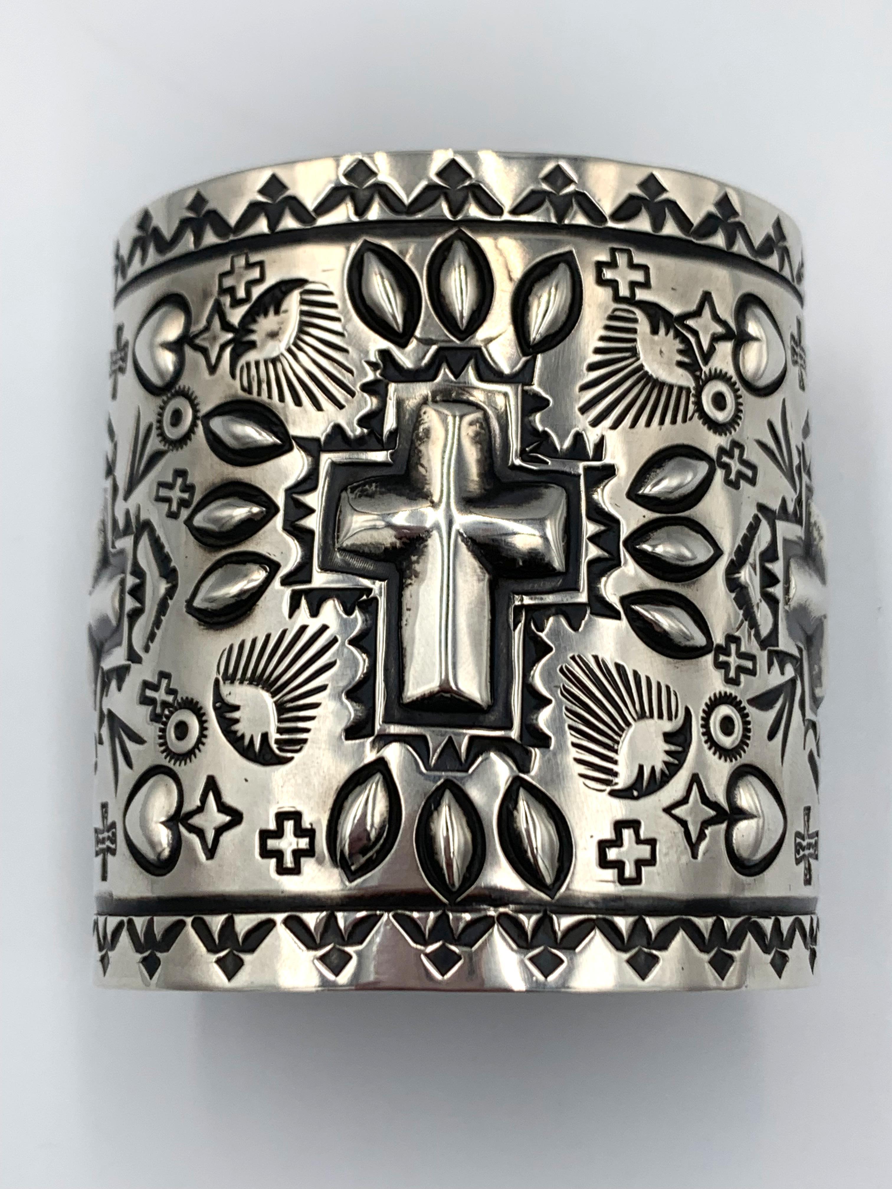 Hand stamped and repousse sterling silver cuff by Navajo silversmith Ronnie Willie. The 2 3/4” cuff has repousse crosses and hearts. The inside is 5 7/8” with a 1 3/8” gap.

Width: 2-3/4”
Gap: 1-3/8”
Total inside circumference: 7-1/4”

About the