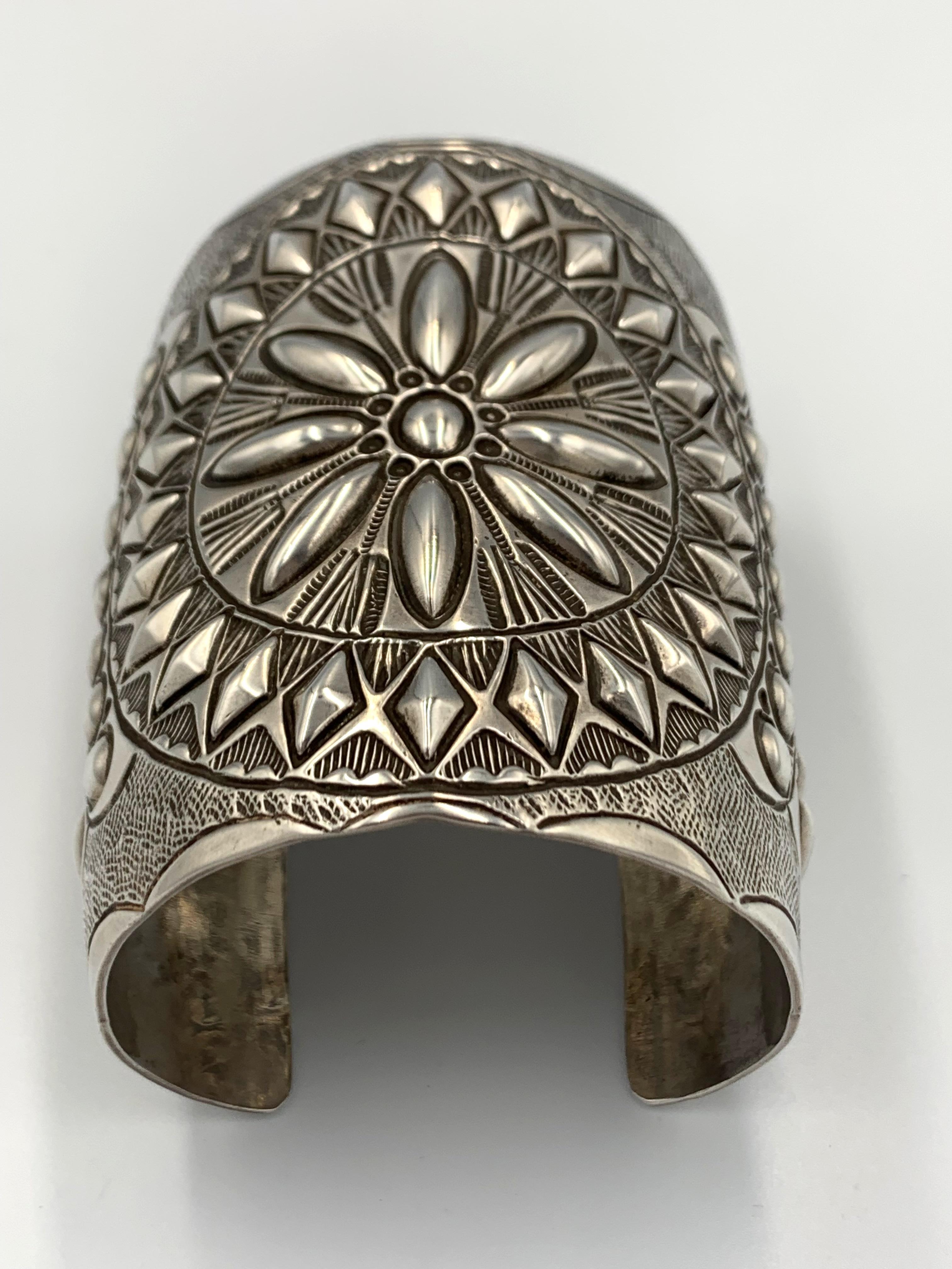 Sterling silver cuff with a hand stamped and repousse pattern by Navajo silversmith Wilbert Benally. The 3 1/8” cuff is made in the style for which Wilbert is known.  The inside is 6” with a 1 3/8” gap. Hallmark: WB

Width: 3-1/8”
Gap: 1-3/8”
Total