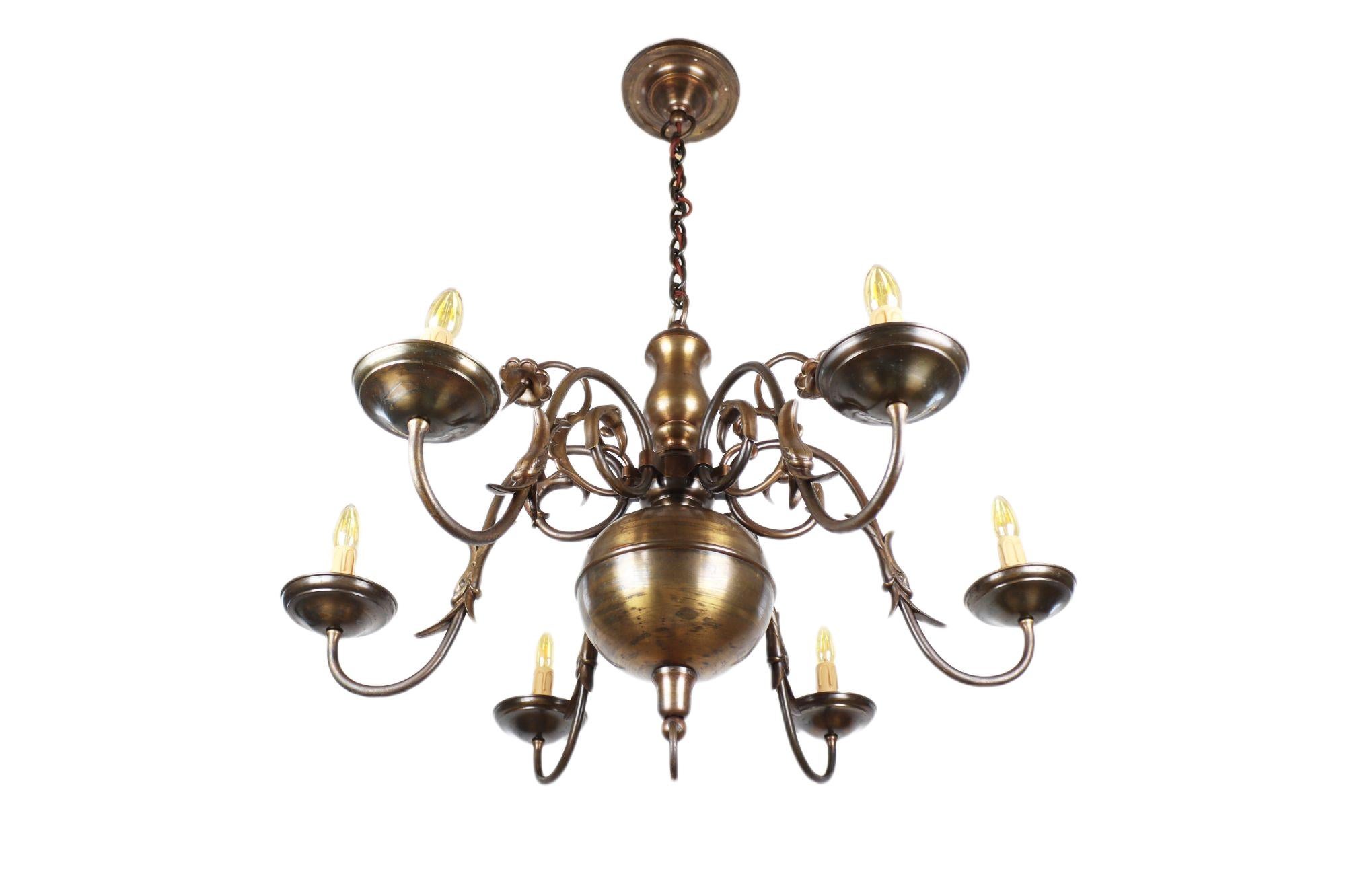 This beautiful representative chandelier from the Art Nouveau period was made around 1918 in the former Austria-Hungary. You will find beautiful decorations in the form of figures on it. The six large arms are finished with candle-shaped sleeves.
