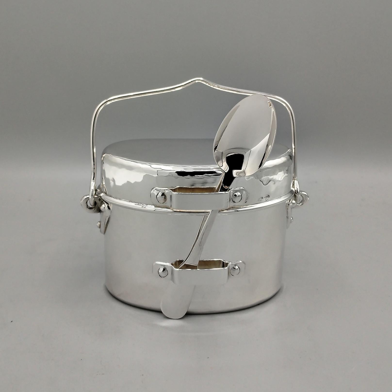 Reproducción en plata 800 maciza de una antigua caja de racionamiento militar italiana con cuchara
El cuerpo está martillado y tiene un asa de alambre montada a los lados con un ojal.
Detrás se ha fijado otro cable plateado, también oscilante, apto