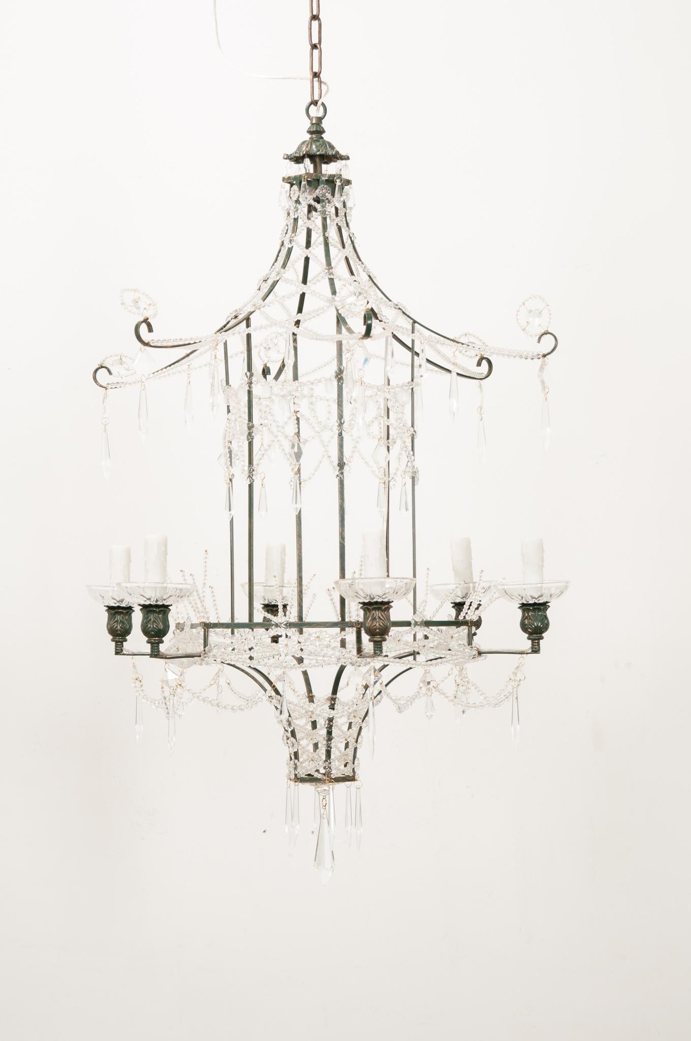 A whimsical painted metal chandelier in the form of a pagoda lantern is a striking composition in Chinoiserie style with a beaded sparkling body of faux crystal pearl swags, rosettes, frosted glass teardrops and multiple cut crystal prisms. Six