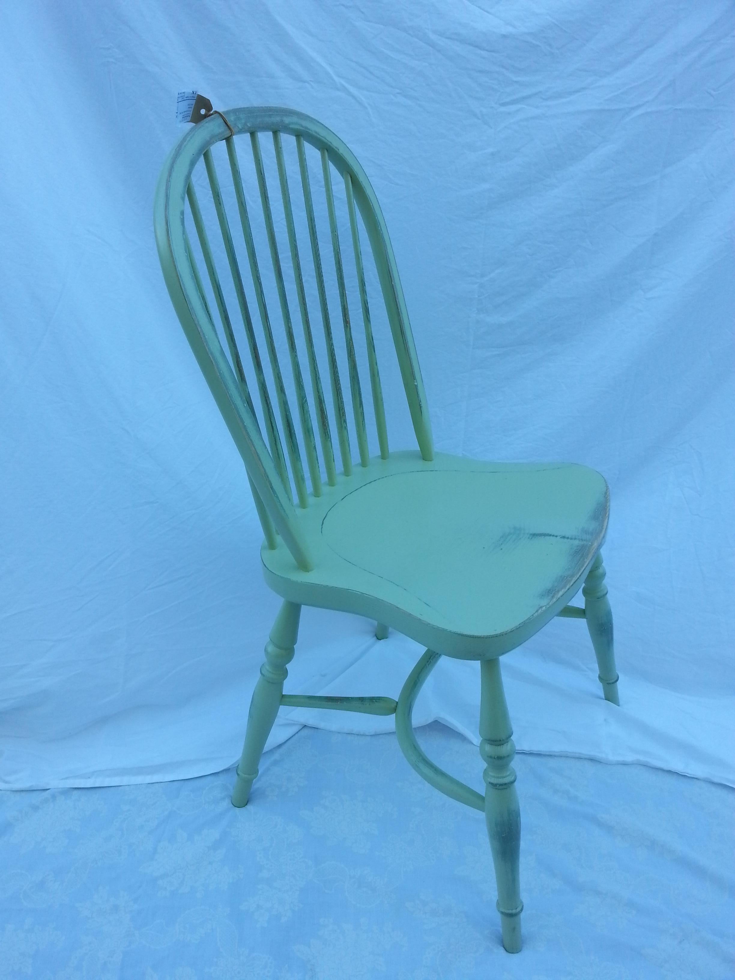 Reproduction spindle back light green side chair with blue underneath.