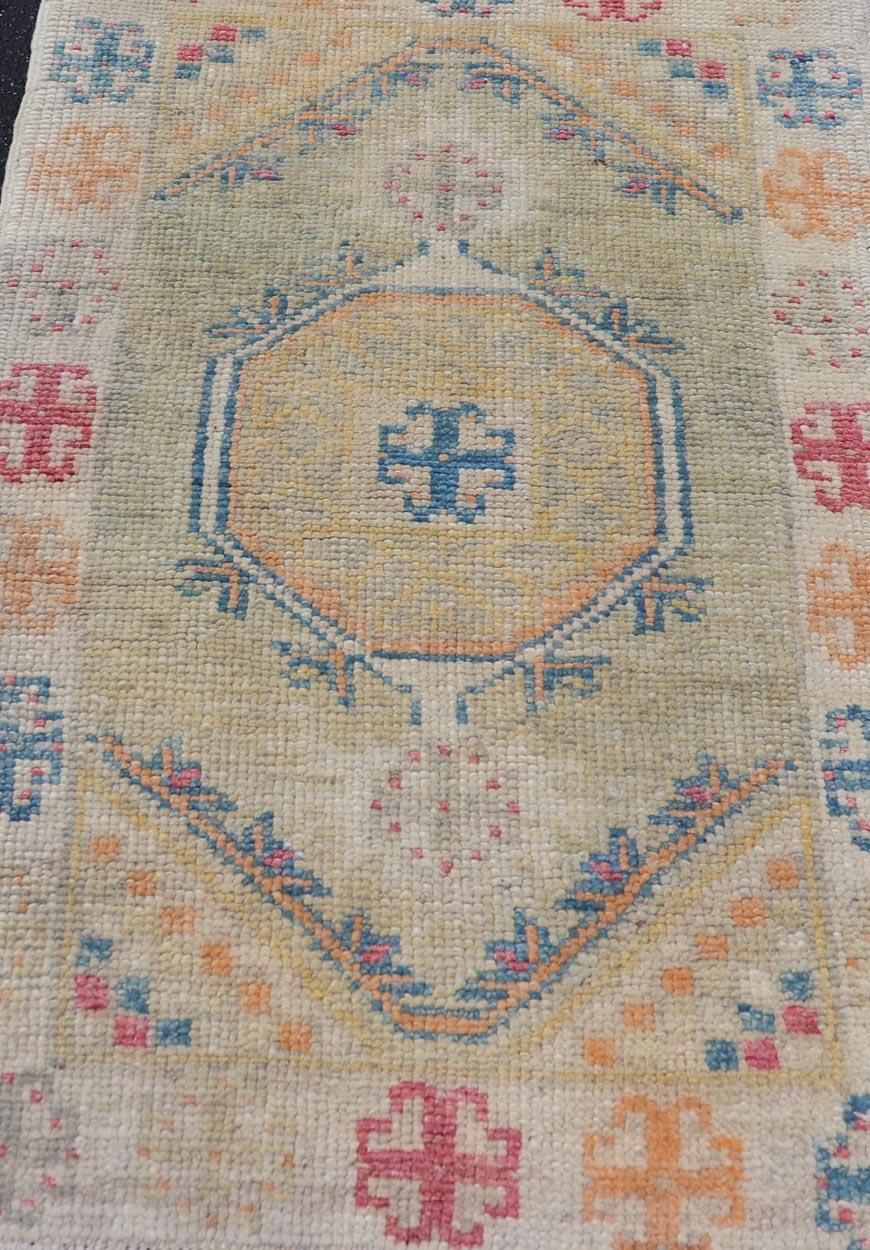 Maße: 2'6 x 4'1 Diese Reproduktion des türkischen Oushak-Teppichs fängt die Essenz der traditionellen türkischen Handwerkskunst mit einem modernen Touch ein. Der Teppich ist in leuchtenden Farben gehalten, darunter Blau-, Gelb-, Orange-, Pink- und