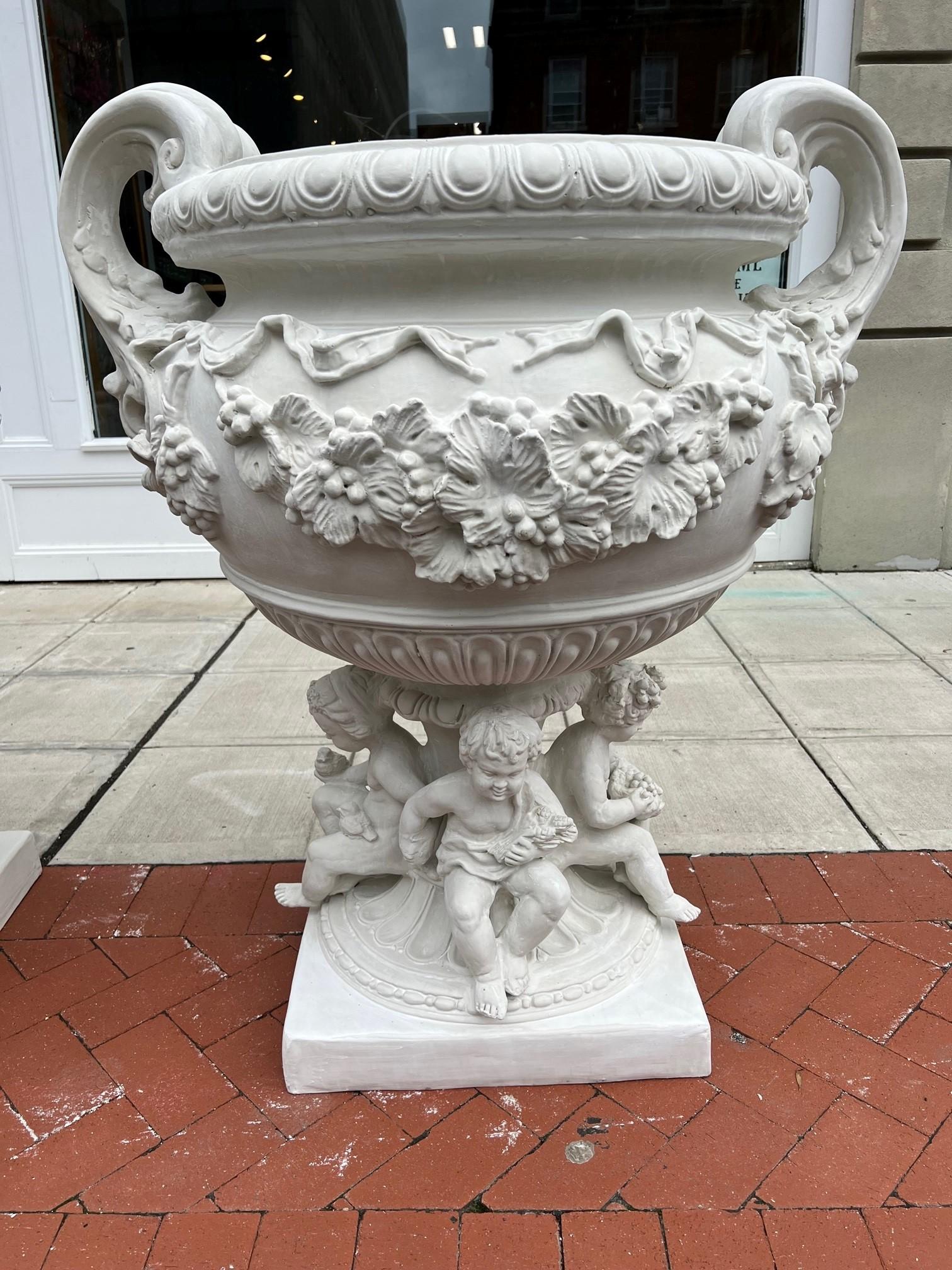 Amazing new reproduction fiberglass urn cast from a vintage glazed terracotta urn from Italy circa 1960s. Embossed with swags of vine leaves, acanthus, grapes with foliage and two monumental handles. Four cherubs sitting around the pedestal holding