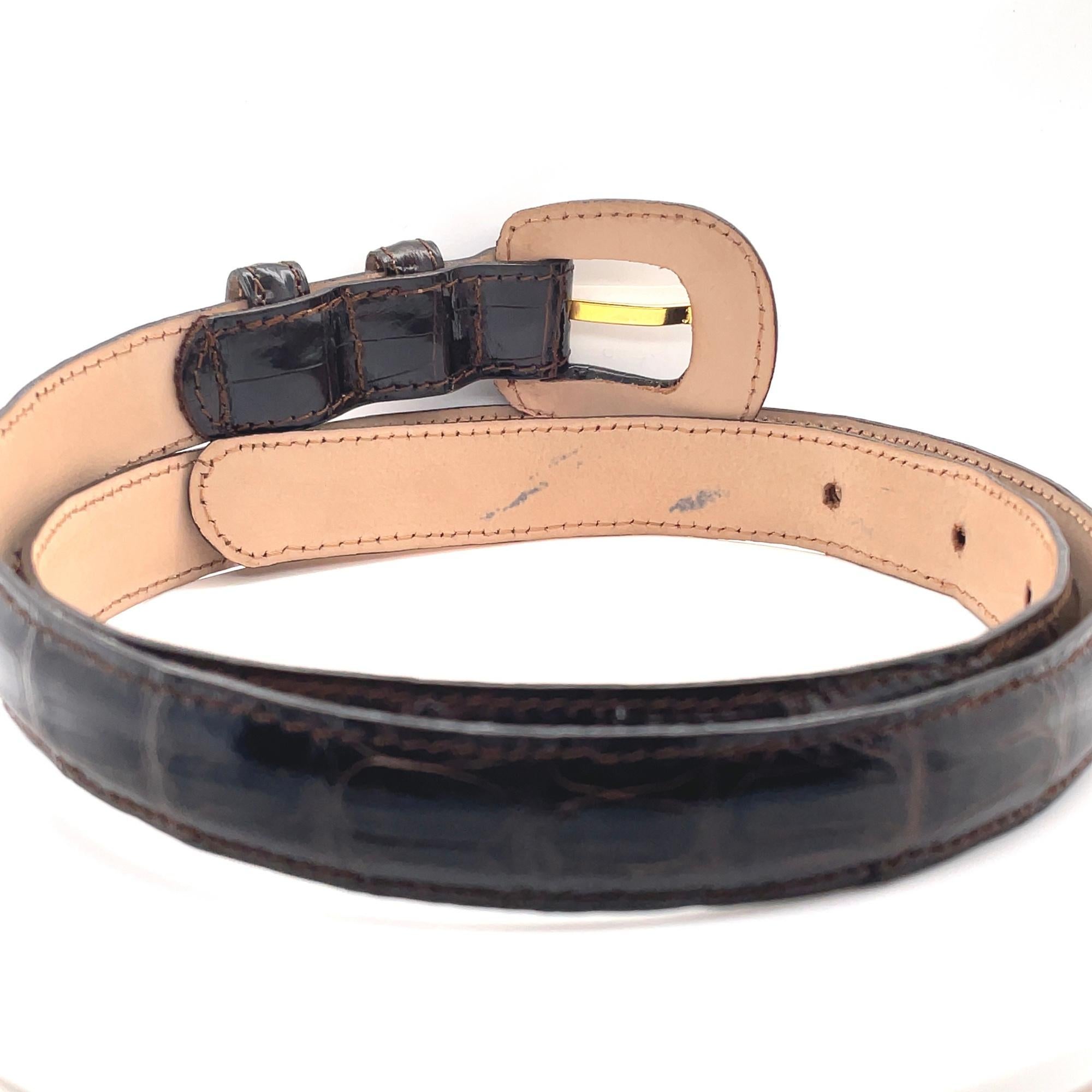 This belt by Reptile's House Italy features a genuine leather pin buckle with gold tone hardware and shiny dark brown genuine leather belt. Buckle measurements: 1.9 inches x 1.8 inches. The belt back is marked with the brand name, logo and size.