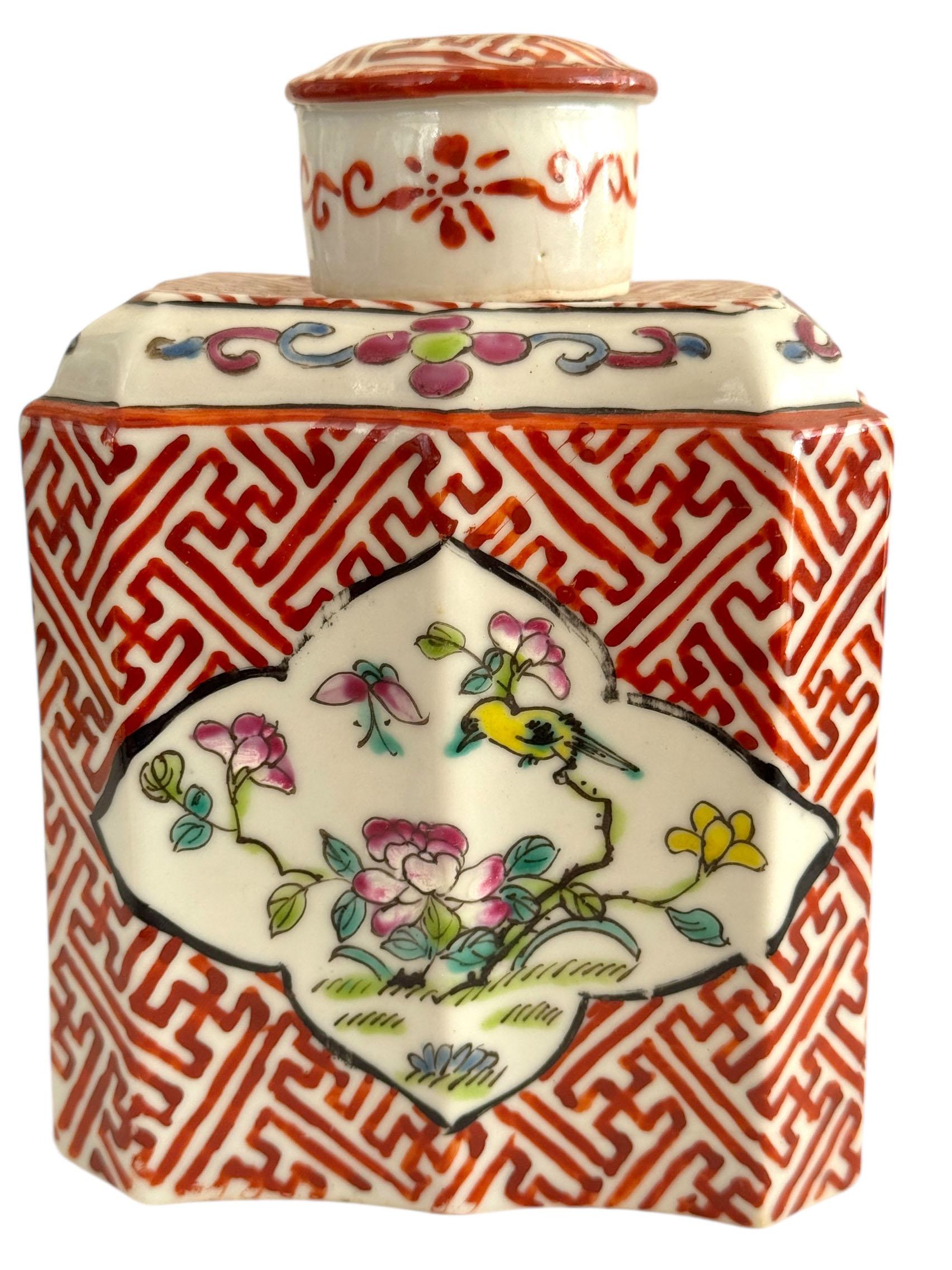 Llamativa caja de té de porcelana china de exportación, del Periodo de la República (hacia 1912-1940). El cuerpo hexagonal está decorado con un atrevido fondo de grecas de llave de color rojo hierro, inserto con reservas de cuatrilóbulos finamente