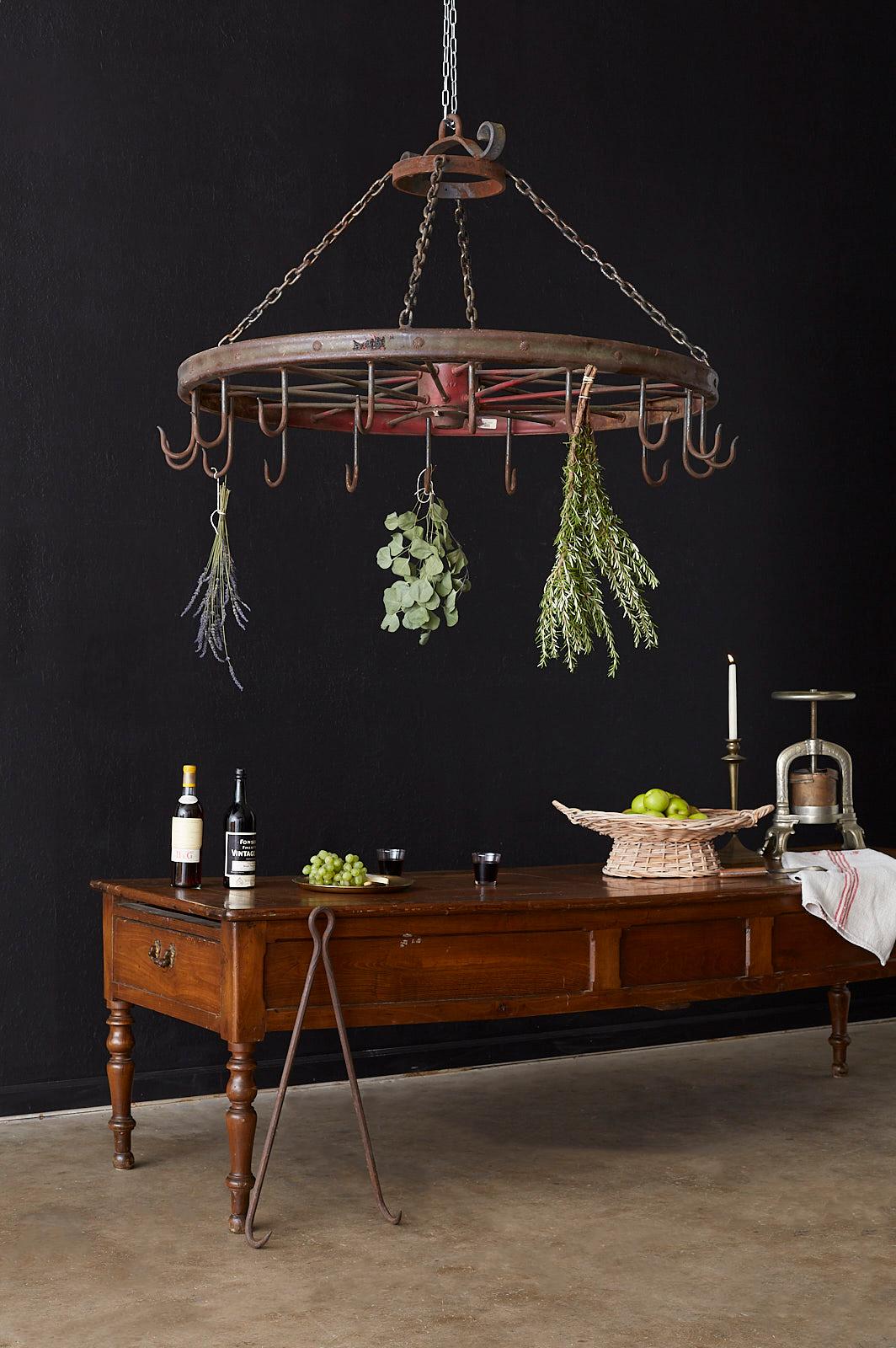Rustic late 19th century American LaFrance iron wagon wheel reclaimed and repurposed into a large butchers rack or pot rack. This piece of American Folk Art can be the centerpiece of a working kitchen or electrified as a rustic chandelier fixture.