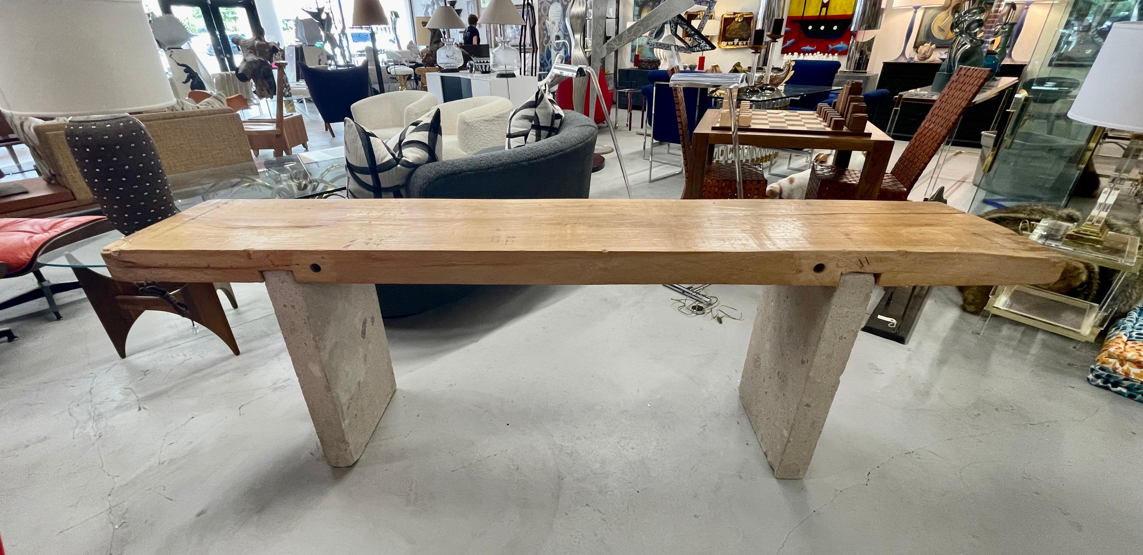 Stunning wood and stone console out of a lovely Palm Springs estate. The top is an old piece of wood, that was likely used in a commercial building that was repurposed and fashioned into a console table in the 1980's. The stone bases were added at