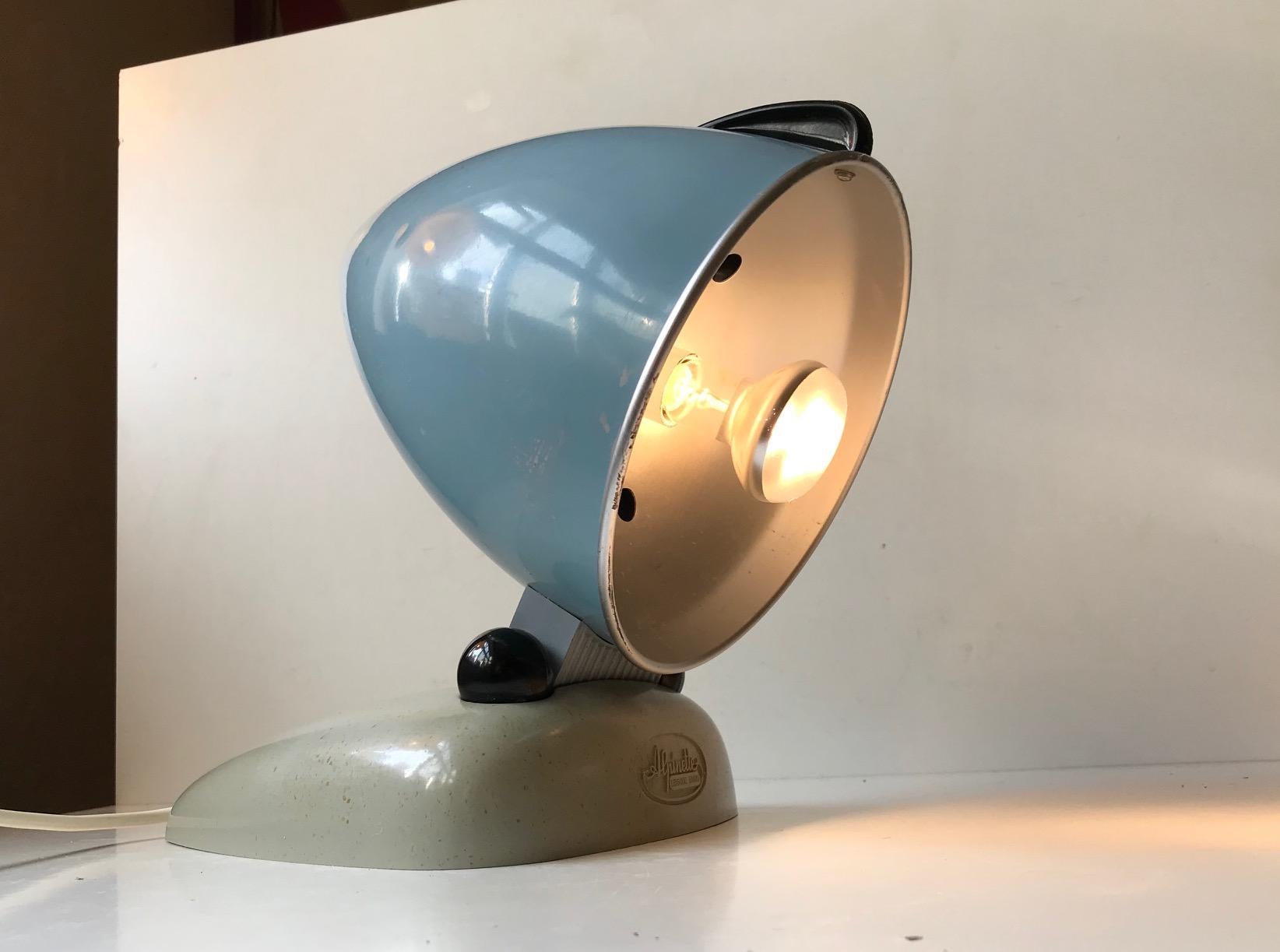 La lampe Alpinette de Hanau était initialement destinée à la luminothérapie. Il date des années 1950 et possède un merveilleux design Bullit - streamline. Ce style a été popularisé par des personnes comme Raymond Loewy et Norman Bel Geddes. Elle a
