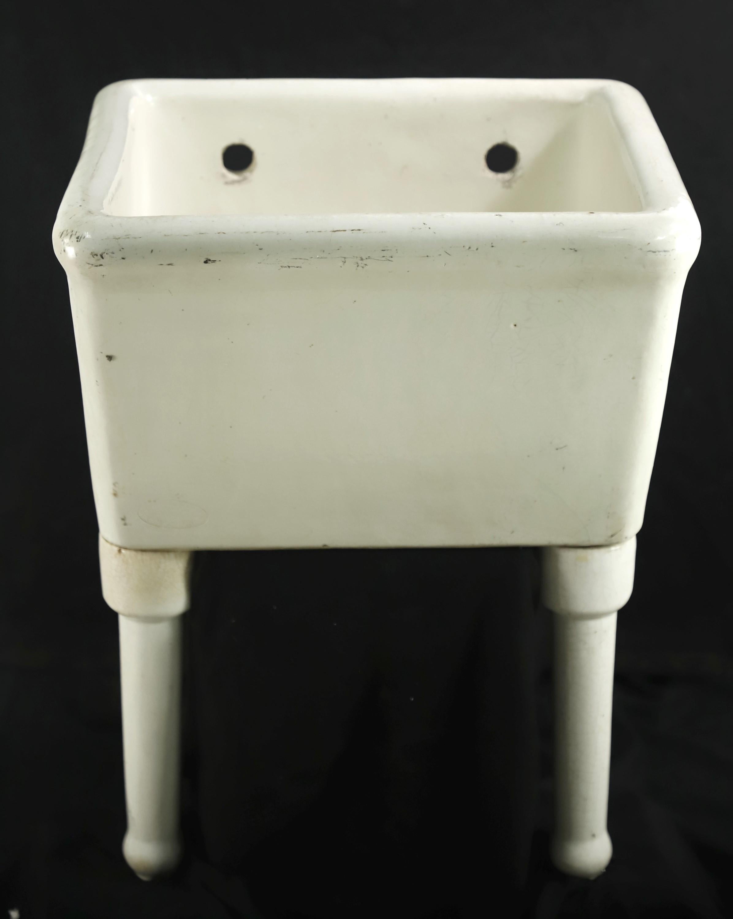 Early 20th Century white wall mounted slop sink supported by two ceramic legs. Made out of earthenware by Chas. Graham Pottery Works in Brooklyn, NY. Minor blemishes. Please see images. Please note, this item is located in our Scranton, PA location.