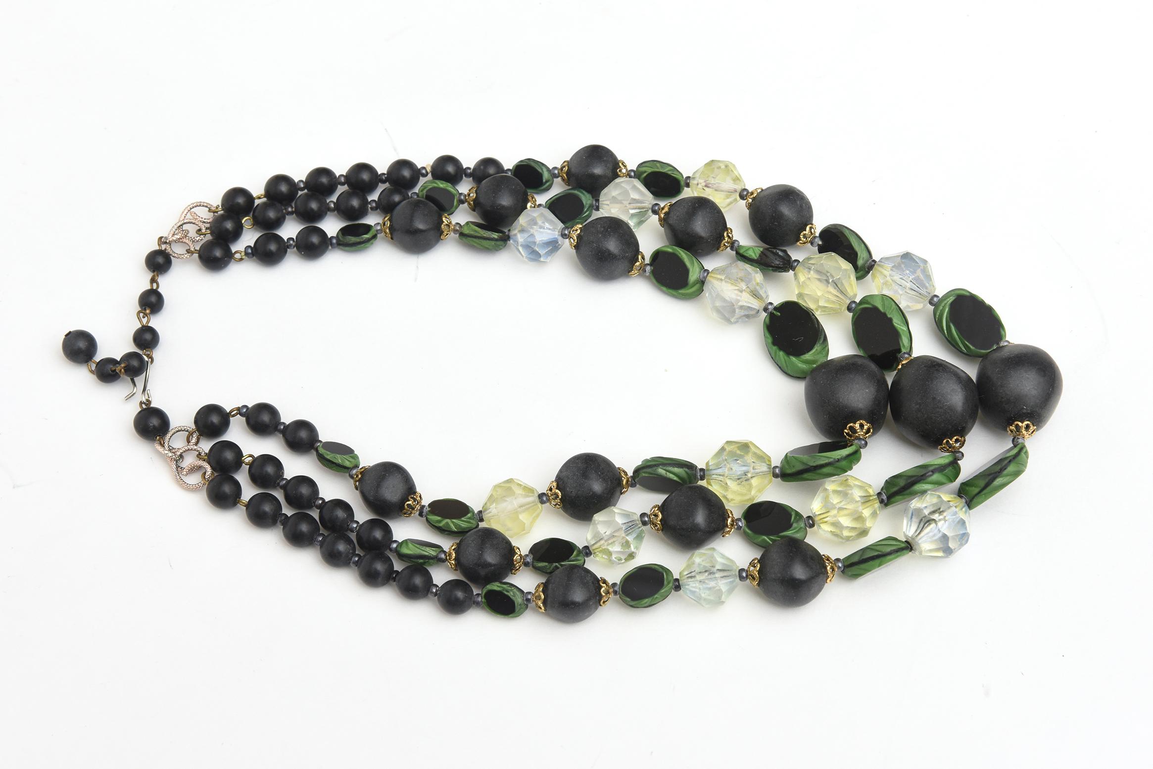 This lovely Czech vintage resin and lucite 3 stand necklace has beautiful colors in shades of green and black disks interspersed with clear resin and lucite shapes. It is from the 50's. Green is a go to color for 2024. It is light in weight and