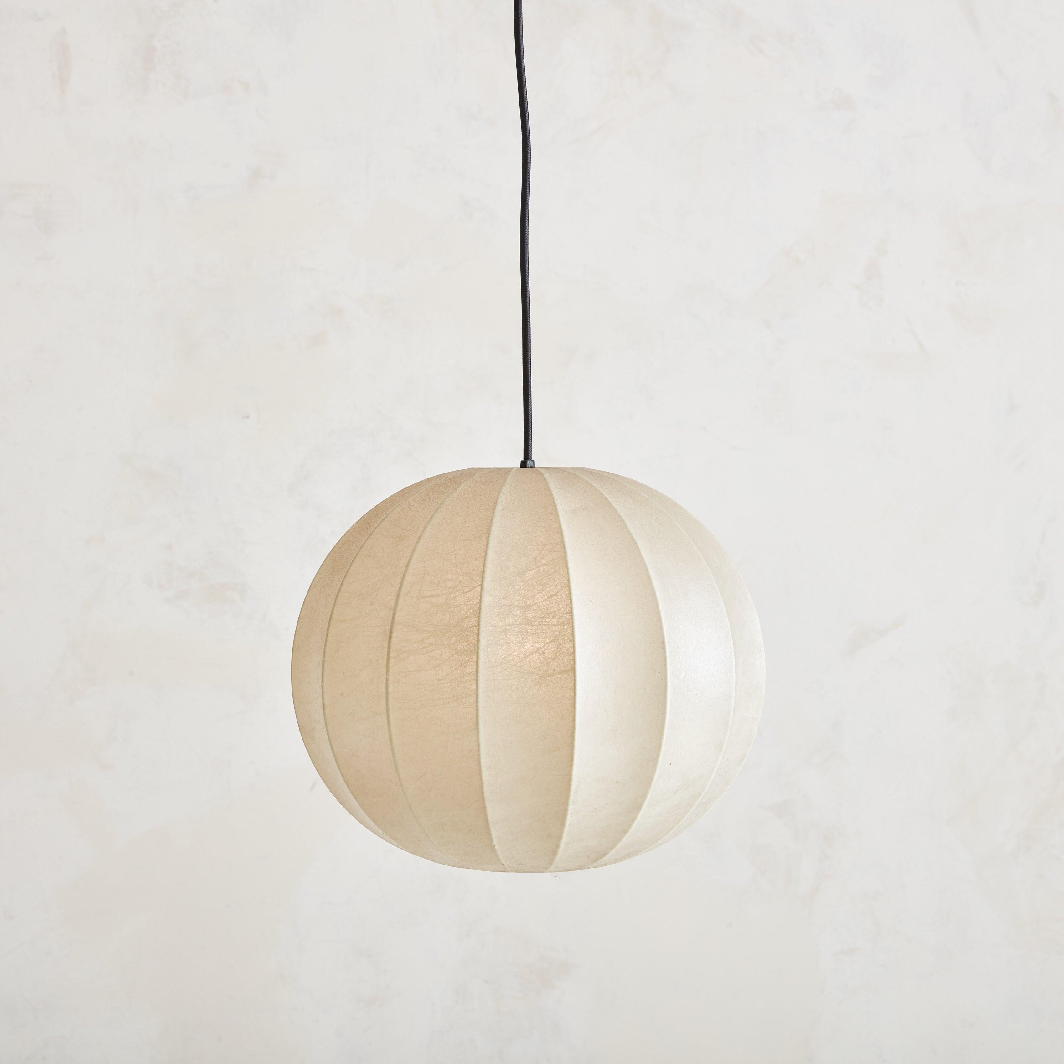 A 1960s Italian cocoon pendant light featuring a metal frame with cream resin shade. This pendant has a cylindrical globe shape with curved channels and a new white metal canopy. When lit, it emanates a warm glow. Unmarked. Sourced in Italy,