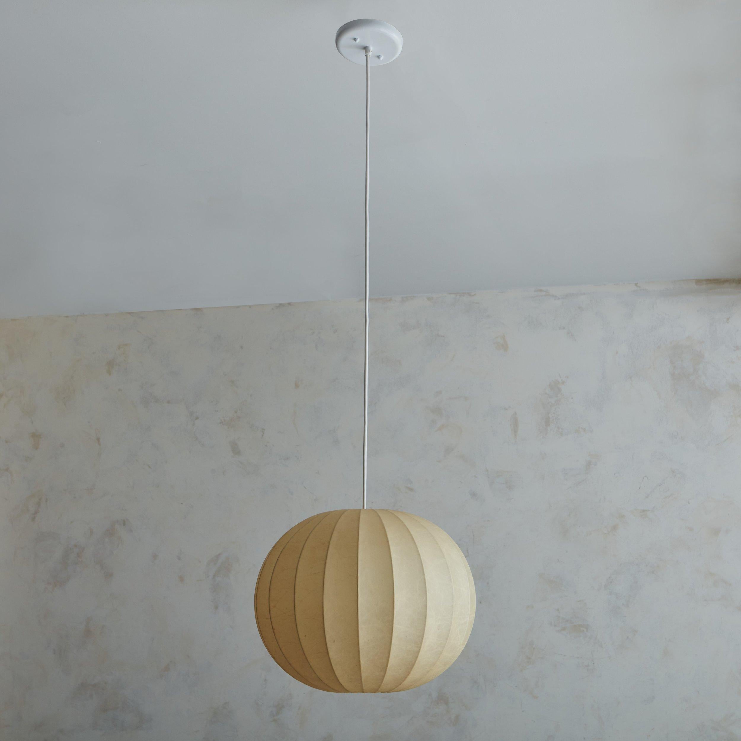 A vintage Italian cocoon pendant light featuring a metal frame with cream resin shade. This pendant has a cylindrical globe shape with curved channels and a new white metal canopy. When lit, it emanates a warm glow. Unmarked. Sourced in Italy, 20th