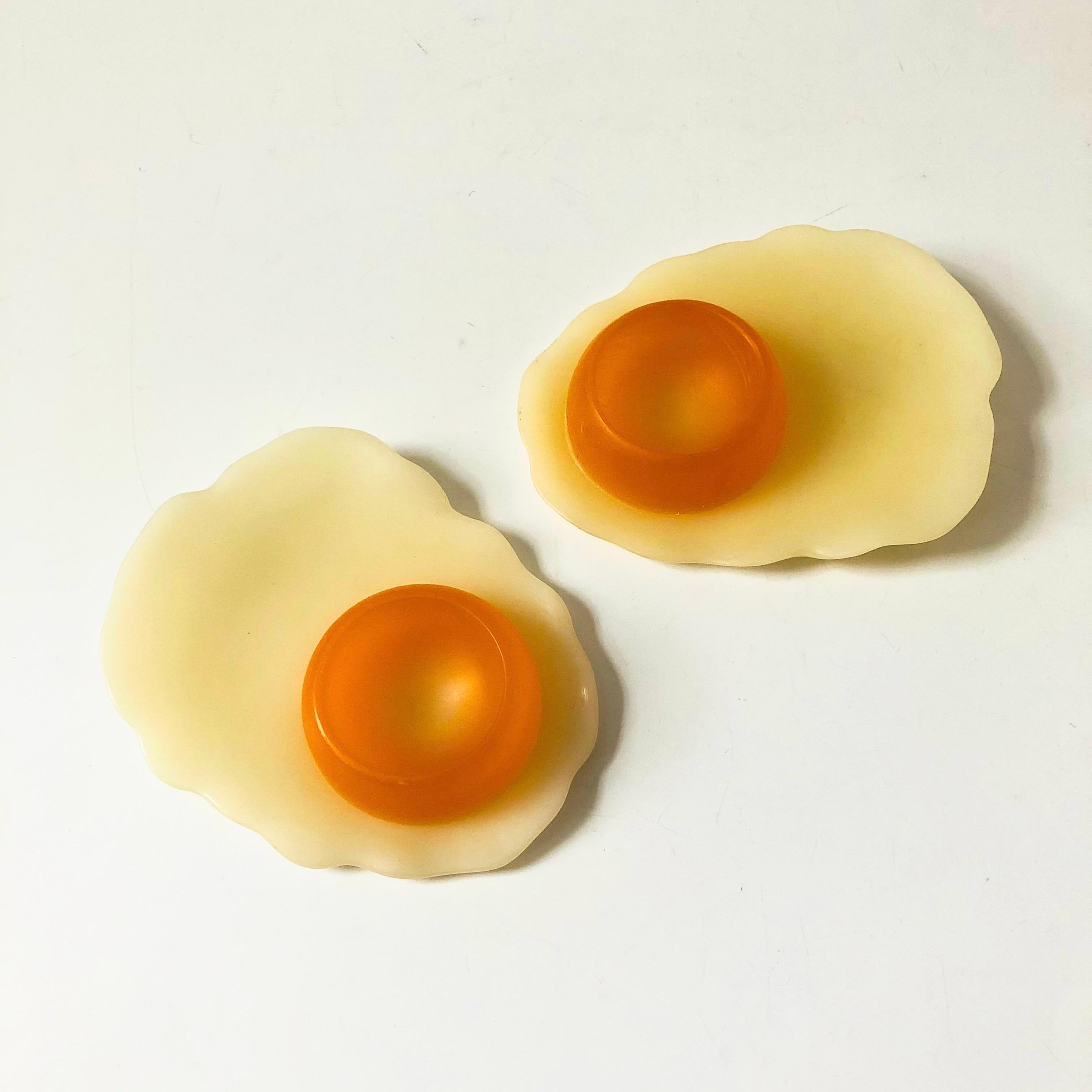 A wonderful pair of vintage novelty egg cups. Made of resin in the shape of fried eggs. An egg can be placed in the orange yolk. These could also be used as candle holders for small votives. Each is marked by the maker, made by Casablanca.

