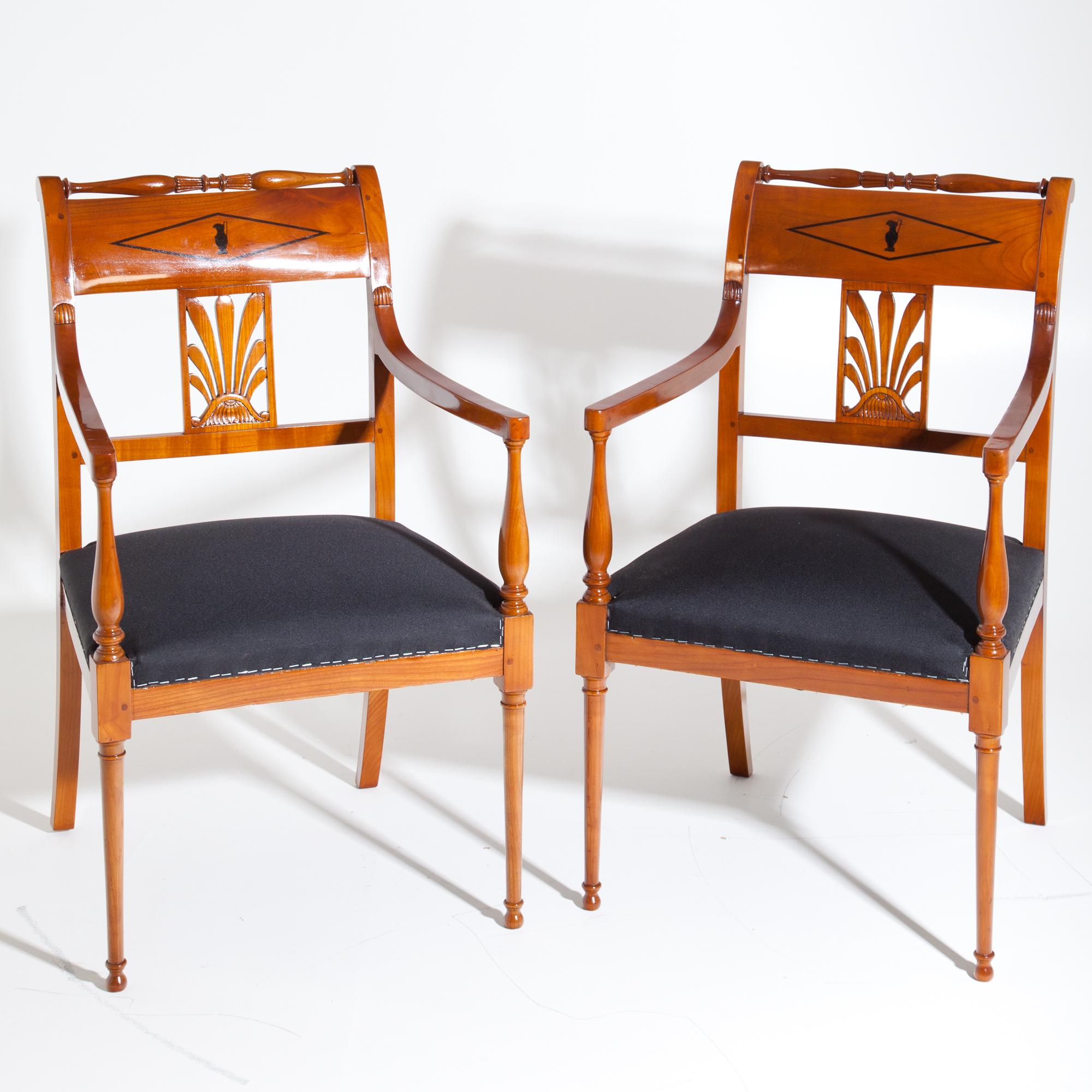 Pair of restoration armchairs made of solid cherry wood standing on conical legs in the front and slightly flared sabre legs in the back. The armrests rest on baluster-shaped supports, the backrests show further baluster-shaped elements as well as