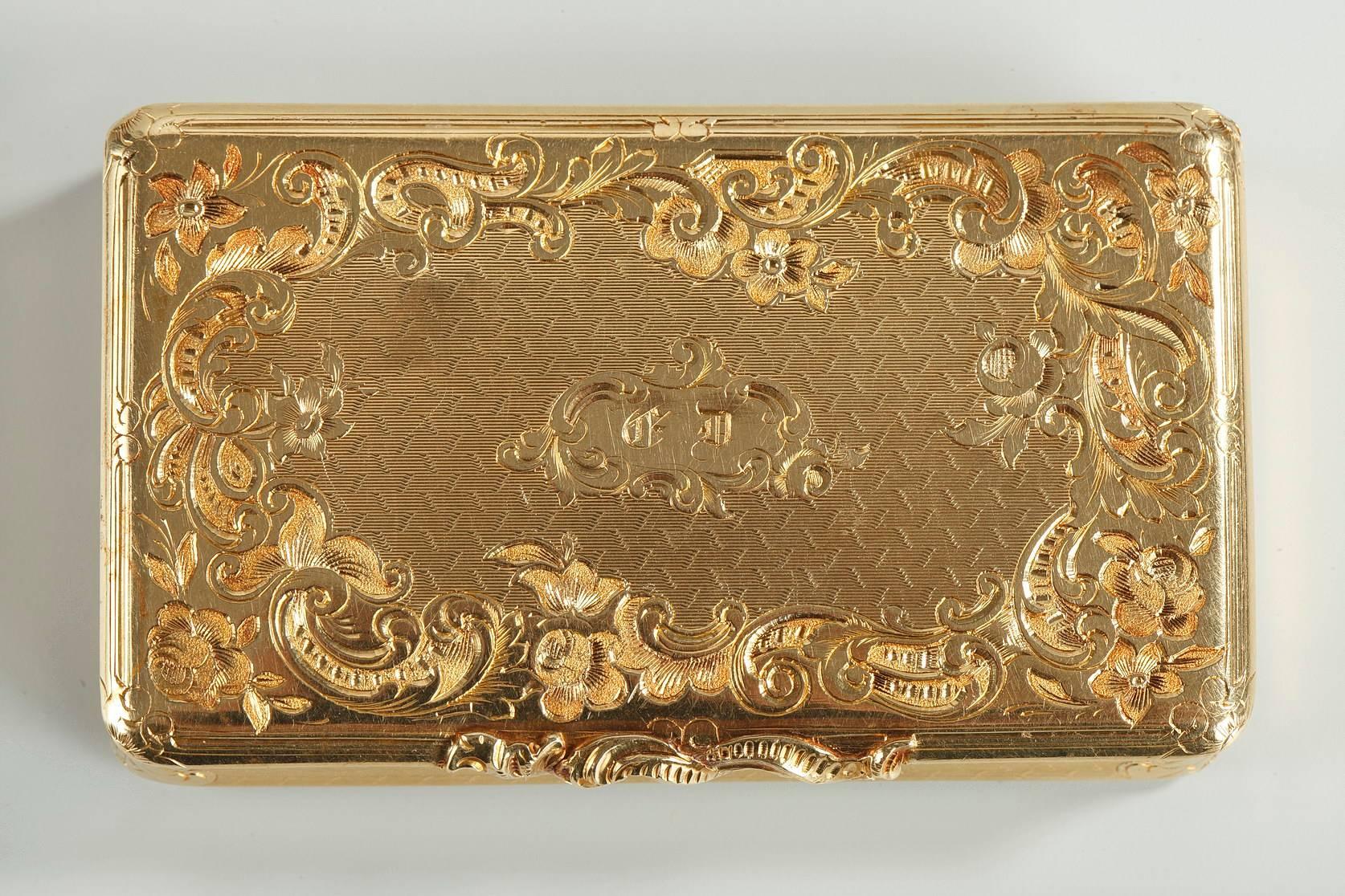 Small, gold snuff box featuring Rocaille motifs. Its cover is embellished with delicately sculpted scrollwork and asymmetrical flowers, which revisits the Rocaille repertoire that was in vogue during the reign of France’s Louis XV. An intricate