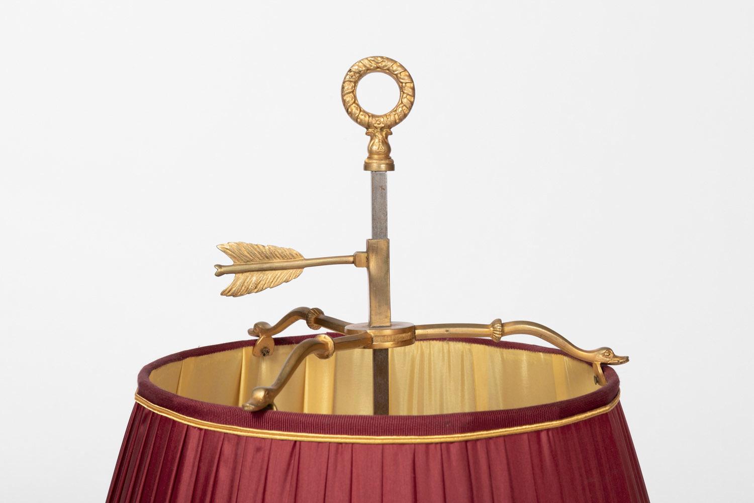 Lampe bouillotte de style Restauration en bronze doré à trois feux.
Base circulaire à bords ajourés de rinceaux feuillagés surmontée d'une petite colonne cannelée supportant une coupe circulaire entourée d'une galerie quinconce ajourée à fond de