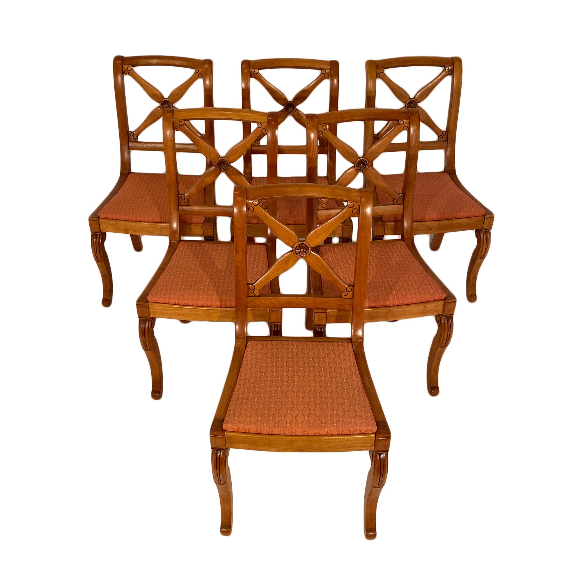 French Restoration dining chairs with additional two armchairs. All are made of hand carved cherrywood with very strong frames. They feature saber back legs and console front legs. The opened back is adorned with stylized crossing swords.

The