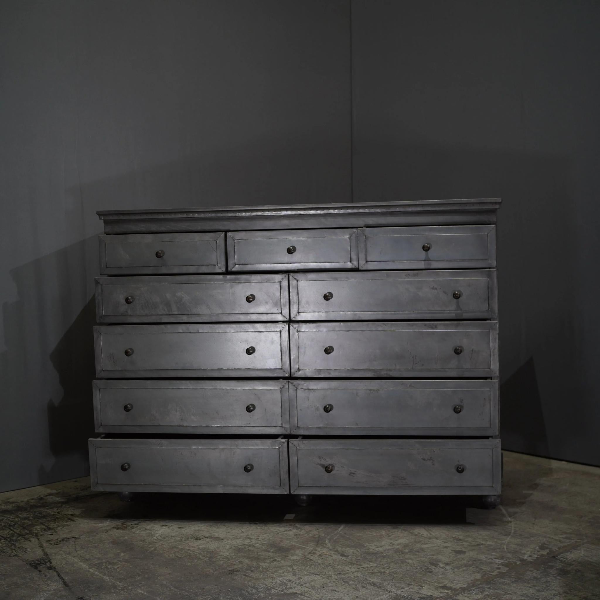 Il comò a 11 cassetti Annecy Metal Wrapped Dresser di Restoration Hardware è un pezzo sorprendente che emana un'eleganza contemporanea e una maestria senza pari. Ognuno degli undici cassetti è meticolosamente rivestito di peltro applicato a mano,
