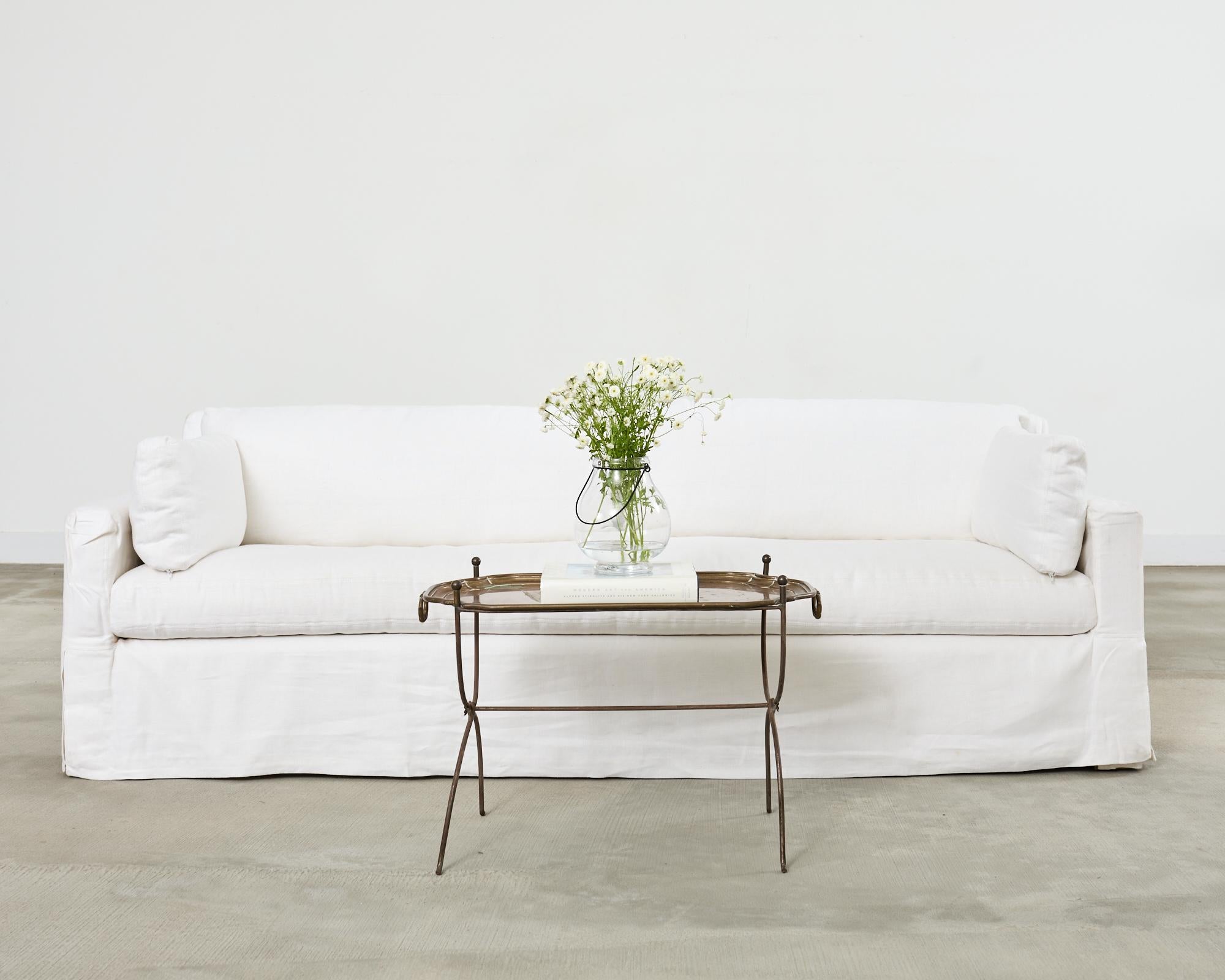 Opulent Belgian linen slipcover sofa settee with a long bench seat by Restoration Hardware. The sofa is constructed from a hardwood frame and features a white linen slipcover over a large down filled bench seat cushion. Heavy and solid with
