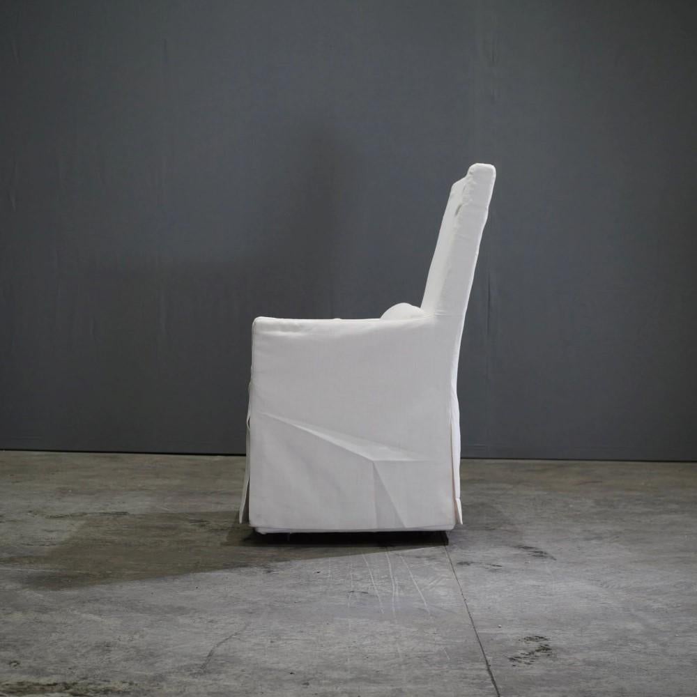The Belgian Track Arm Slipcovered Dining Armchair exudes timeless elegance with its classic design and luxurious comfort. Crafted with a keen eye for detail, this chair features a robust hardwood frame paired with a sumptuous slipcover made from