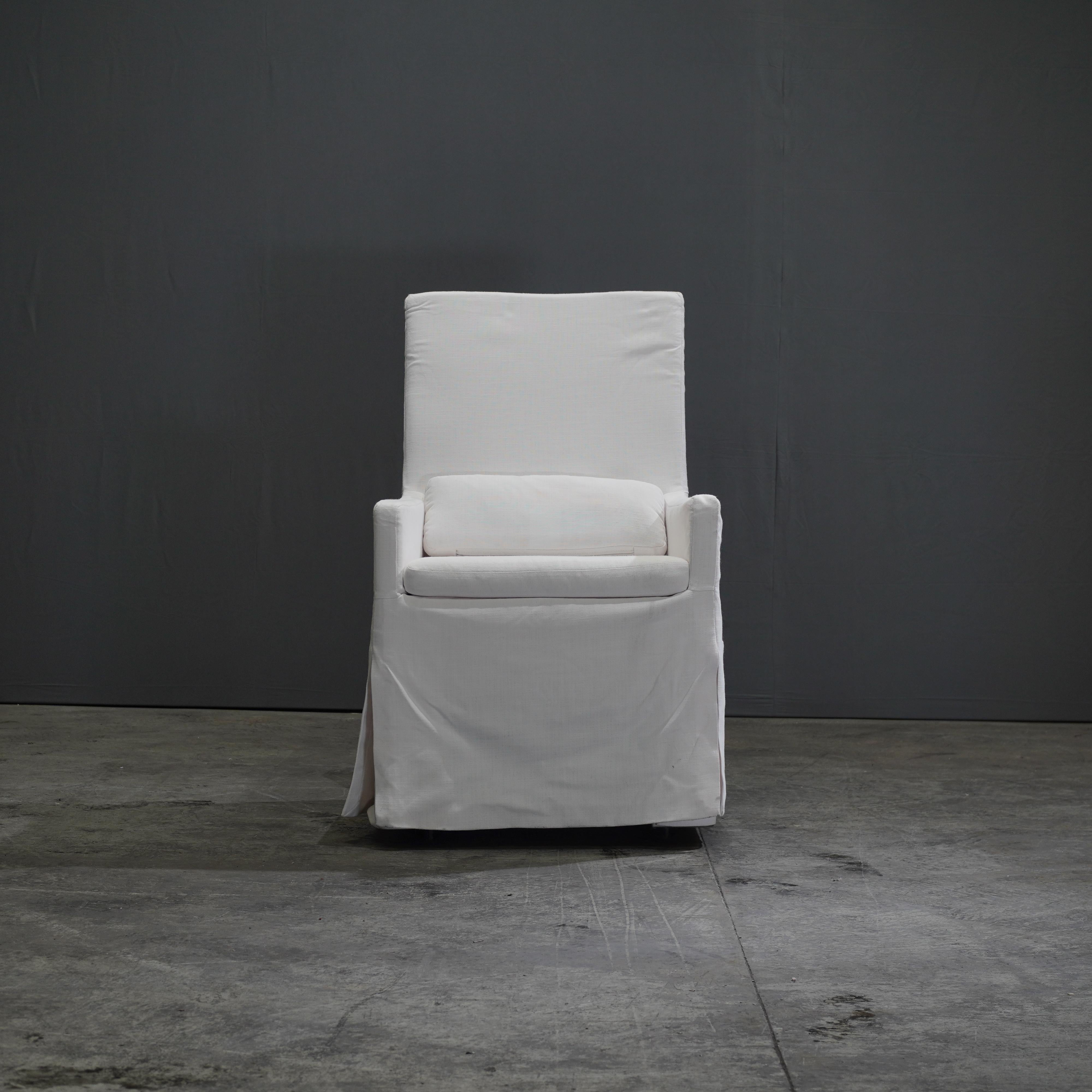 The Belgian Track Arm Slipcovered Dining Armchair exudes timeless elegance with its classic design and luxurious comfort. Crafted with a keen eye for detail, this chair features a robust hardwood frame paired with a sumptuous slipcover made from