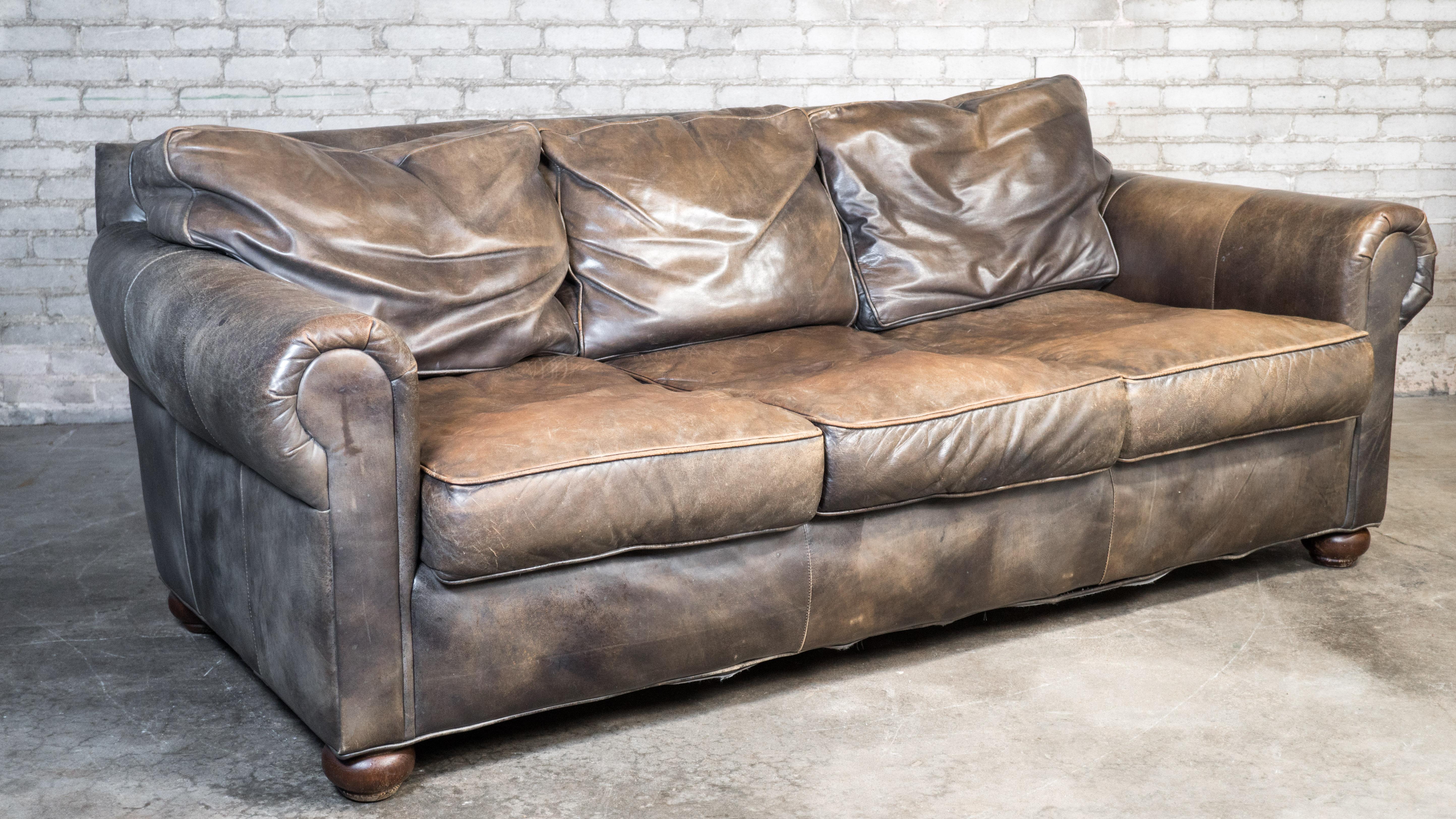 Restoration Hardware Three-Seater Lancaster Leather Sofa. Presented in distressed grayish brown leather. Premium down-feather filled cushions and soft, supple leather, contribute to immense comfort and a delightful lounging experience. Traditional
