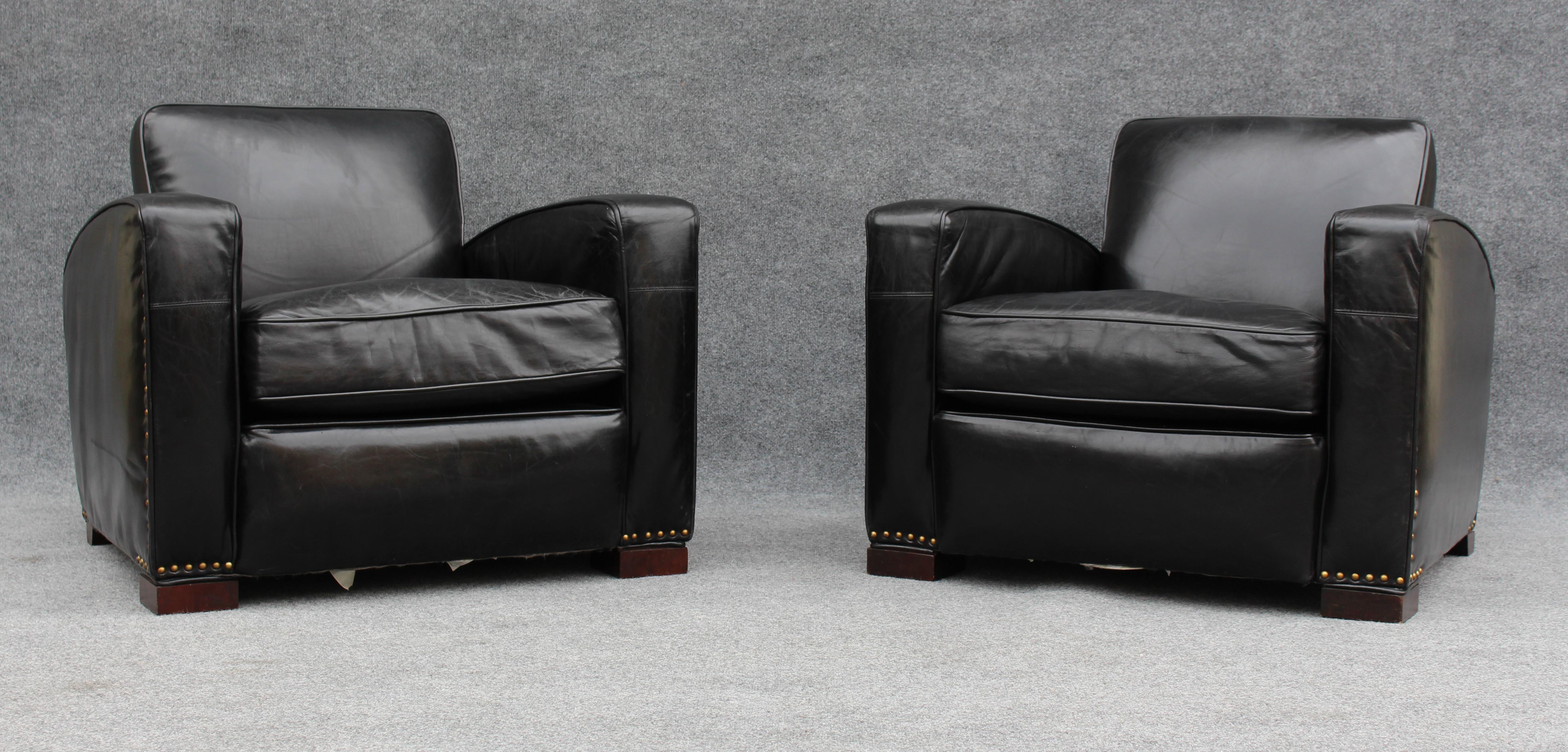 Reminiscent of chairs found in the great reading rooms of Europe, this pair of lounge chairs features a sleek curved design with thick arms, backs, and seat cushions. Reinforced from the interior with a hardwood frame, the pair is covered in black