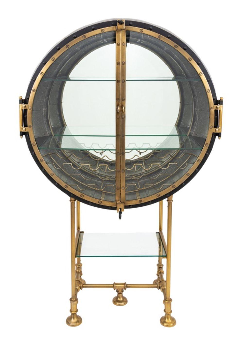 Restoration Hardware Porthole Bar, galvanized iron and brass, the glass door opening to a mirrored interior with two glass shelves and 13 wine bottle holders, with mirror to reverse and glass shelf below atop a pipework base. 63.5
