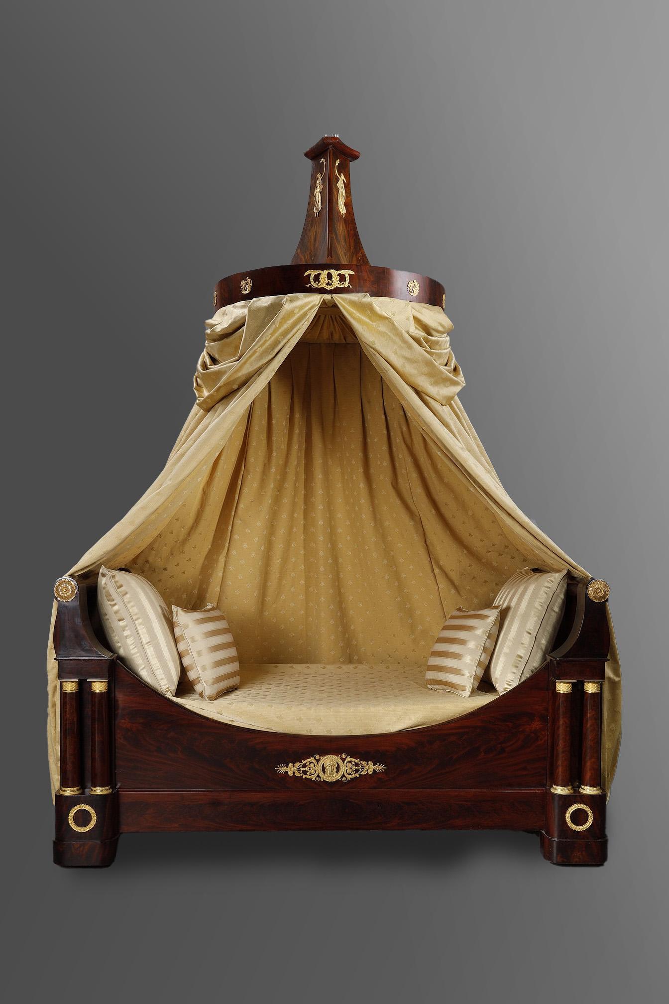 Restoration-period mahogany-veneered boat-shaped sofa-bed with slightly inverted headboard. The front is soberly adorned with an ormolu plaque featuring scrolls and fleurons framing a finely chased female face with antique hairstyle in a laurel