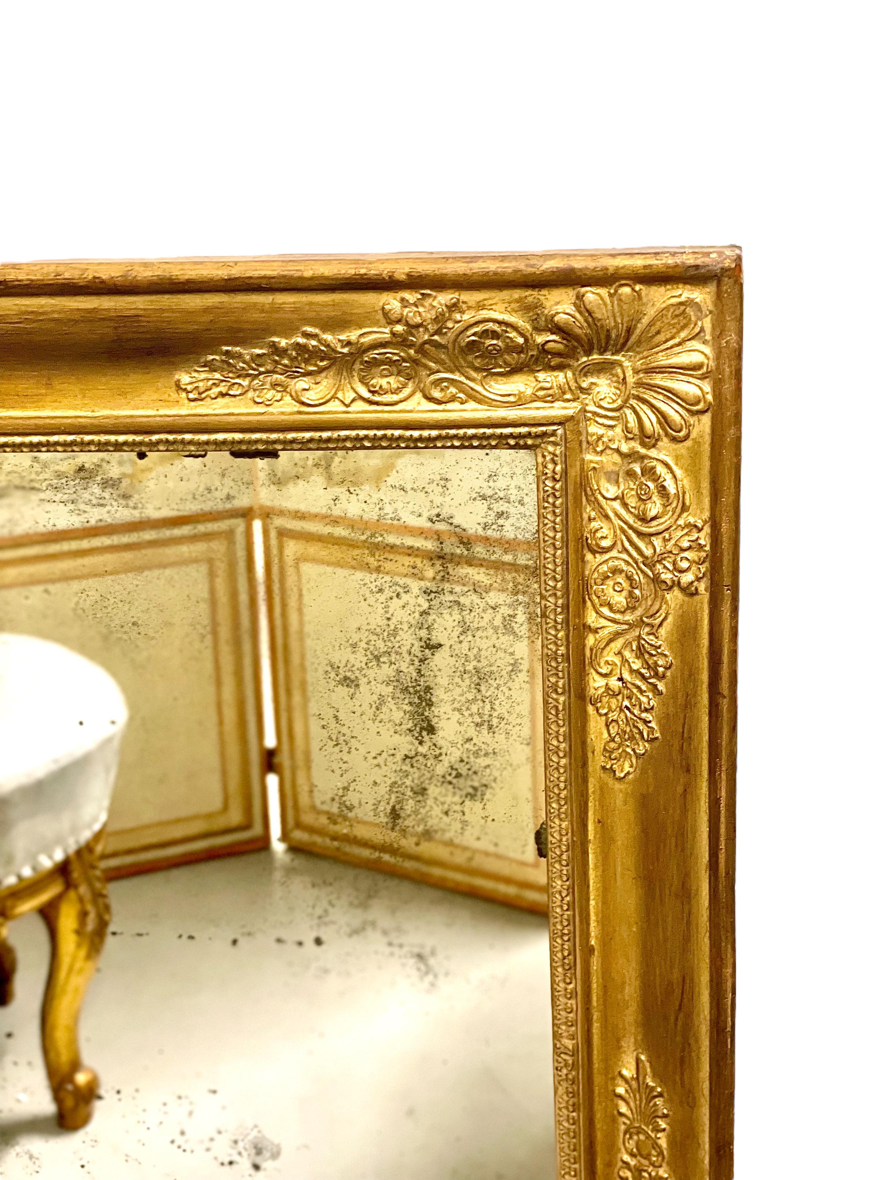 Beautiful antique rectangular mirror from the French Restoration period, in a wood and gilded stucco frame. Each corner is adorned with a moulded palmette and floral flourish, while the four sides of the frame display a frieze of water leaves,