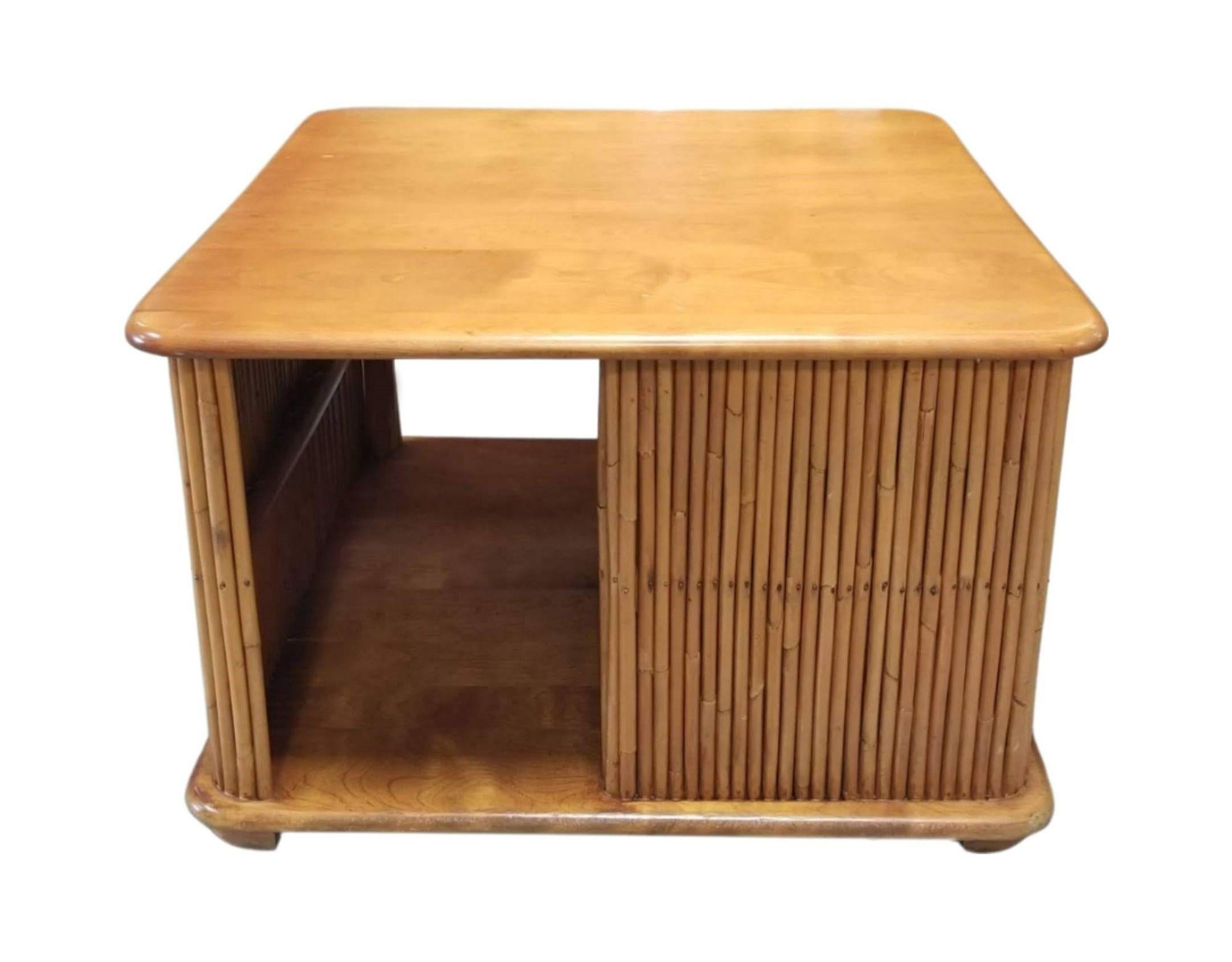Unique square coffee table with bottom shelf and compartments separated by vertically stacked reed rattan sides, featuring a maple wood top. Original by designer Paul Frankl.
There are minor scratches on table top, as shown in photos.
We only