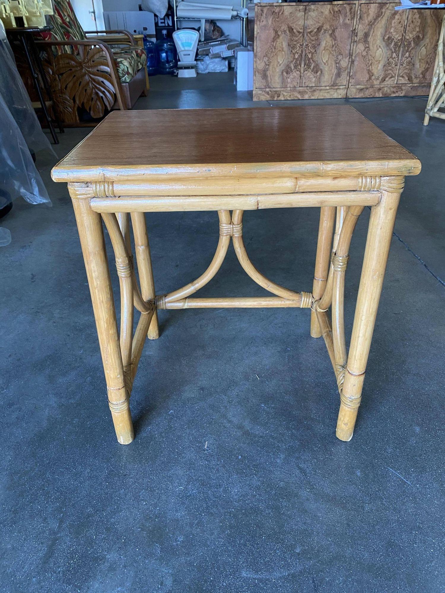 Mid-Century era rattan side table drink stand featuring a bent rattan structure with a koa wood tabletop. The table features unique decorative 