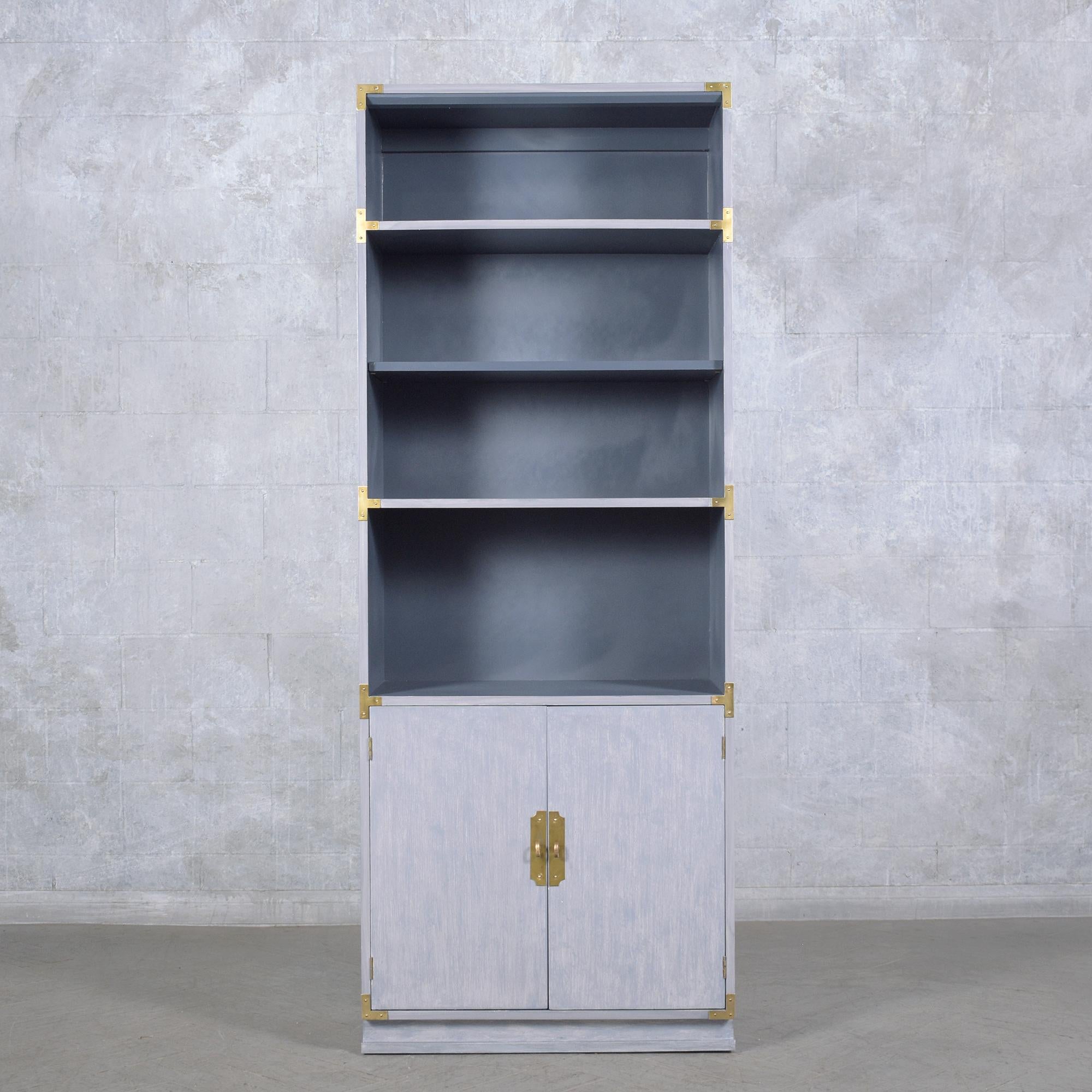 Explore the elegance of our vintage 1960s Campaign-style bookshelf, meticulously restored and refinished by our in-house team of professional craftsmen. This mid-century modern bookcase is well crafted and features a unique custom grey and dark grey