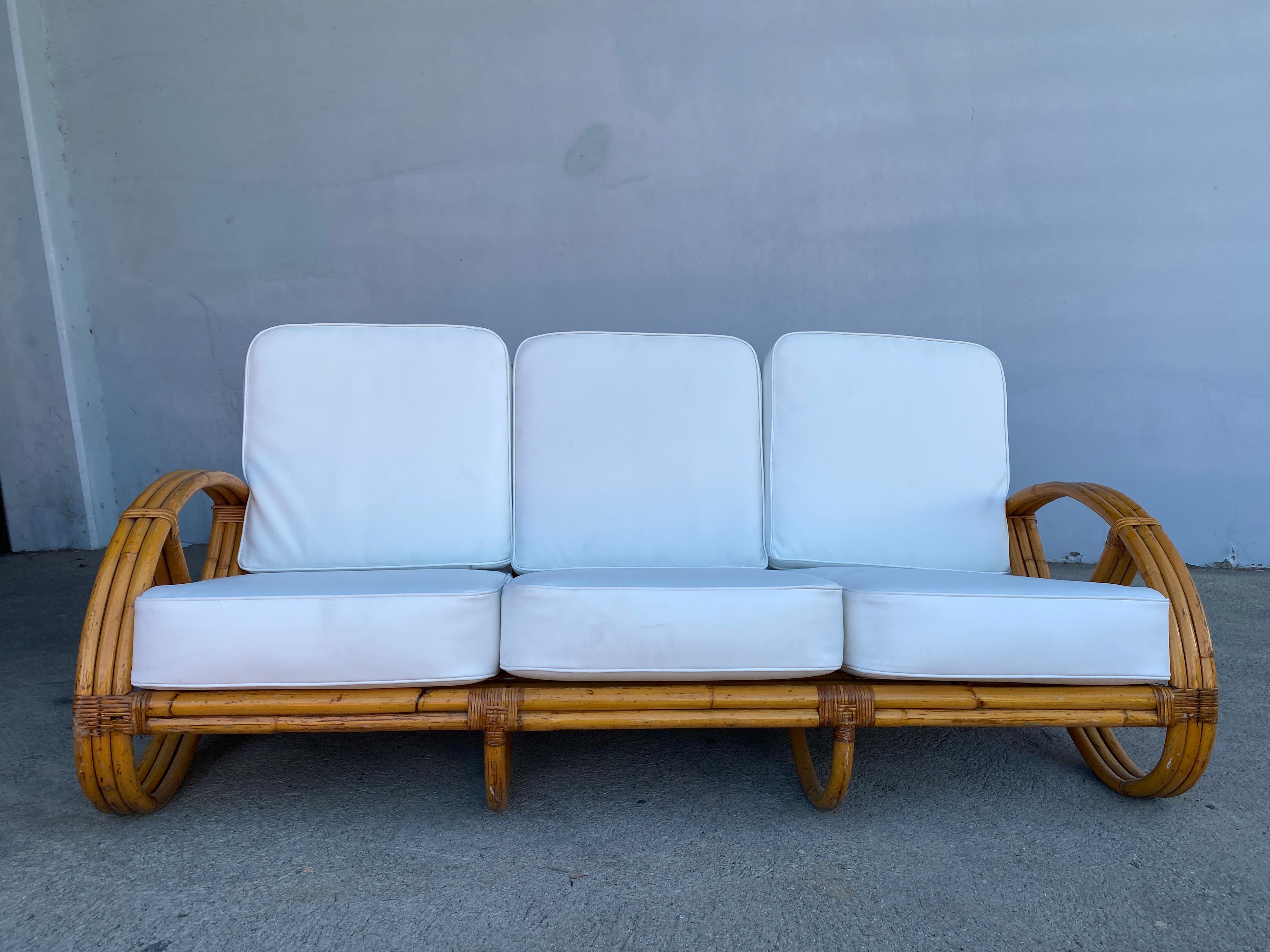 Dieses runde 3/4-Brezel-4-Sitzer-Sofa mit dreifach gerundeten Brezel-Armen und offenem Gestell.

Für Sie wie neu restauriert. 
 
Tropical Sun Rattan wurde 1934 am 117 West Colorado Blvd in Pasadena gegründet. Bis 1938 hatten wir