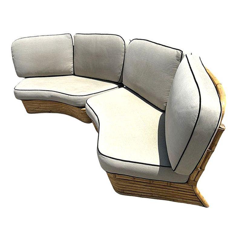 This beautifully restored Paul Frankl-inspired Mid-Century rattan curved sectional sofa with four seats in two sections. This sofa features a stacked rattan base with a pole rattan seat back and is decorated with wicker rattan wrappings. The sofa