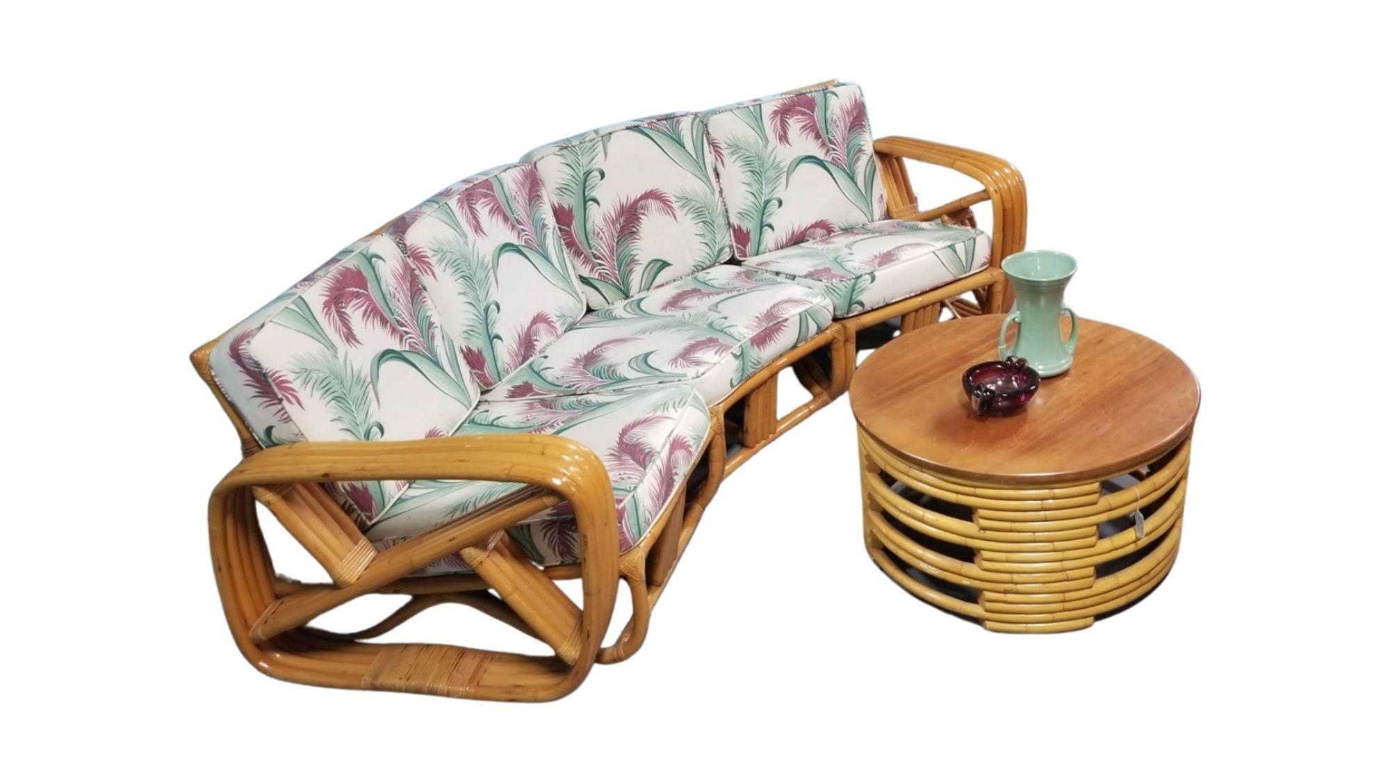 Mid-Century restored rattan living room set featuring a 3-piece sectional sofa with square pretzel arms, a round coffee table, and a two-tiered side table. Also included is an original 1950s murano ashtray and blue art pottery vase.

Circa