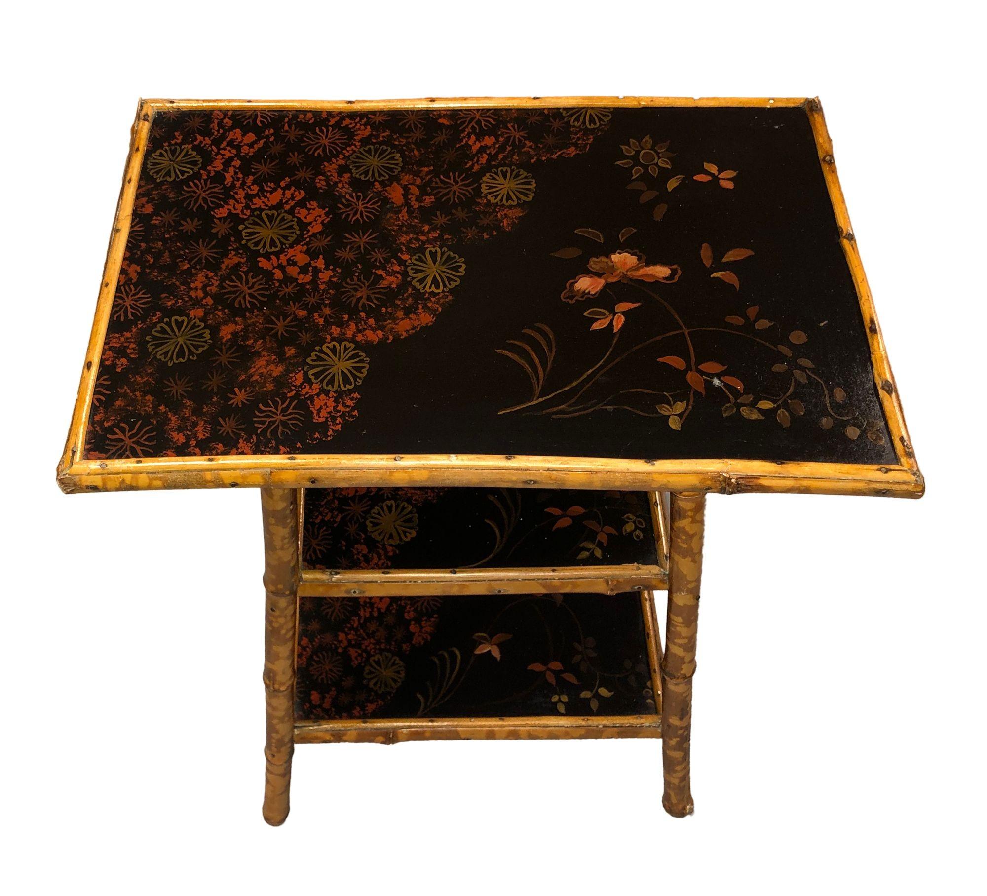 Table d'appoint en bambou tigré de la fin de l'époque victorienne avec 3 niveaux de plateaux floraux peints à la main. Les meubles en bambou de cette époque sont généralement associés au mouvement astétique et se caractérisent par des lignes et des