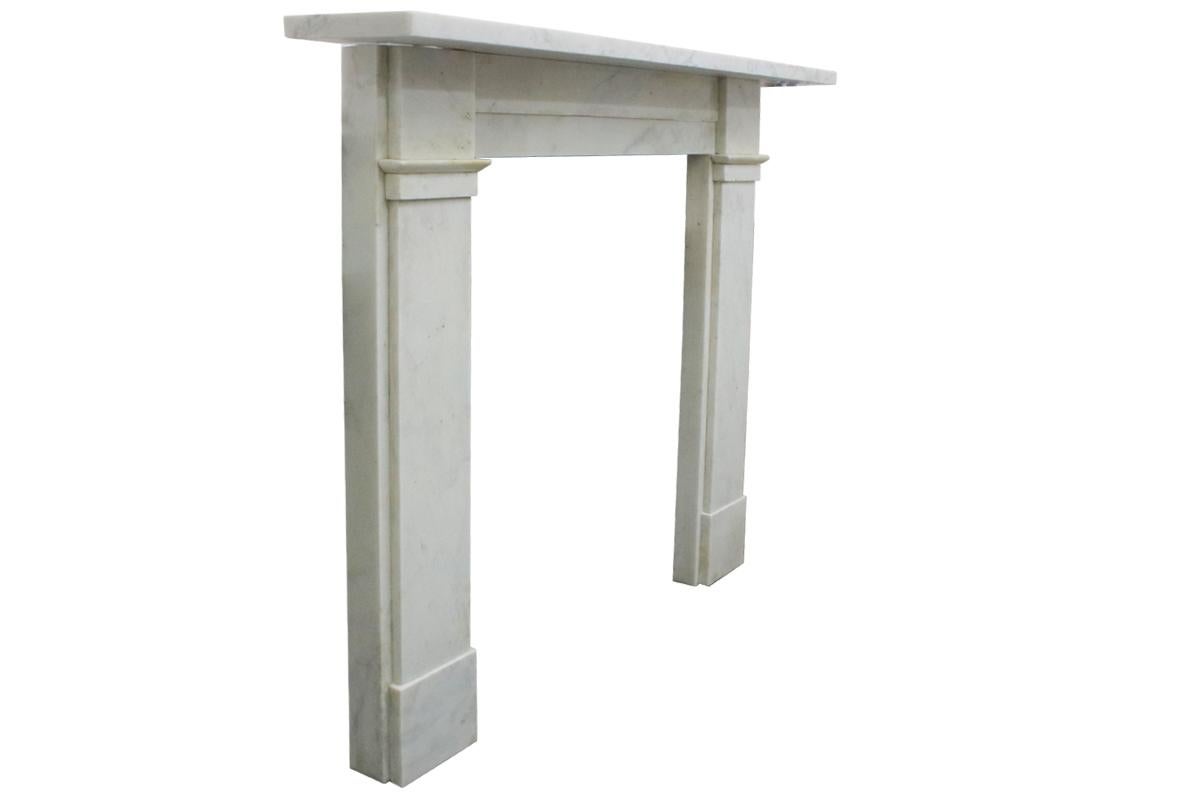 Restored antique 19th century early Victorian near statuary white marble fireplace surround of simple construction with square capitals above unadorned jambs and flanking a two part stepped frieze. Circa 1840. 

For detailed sizes please see