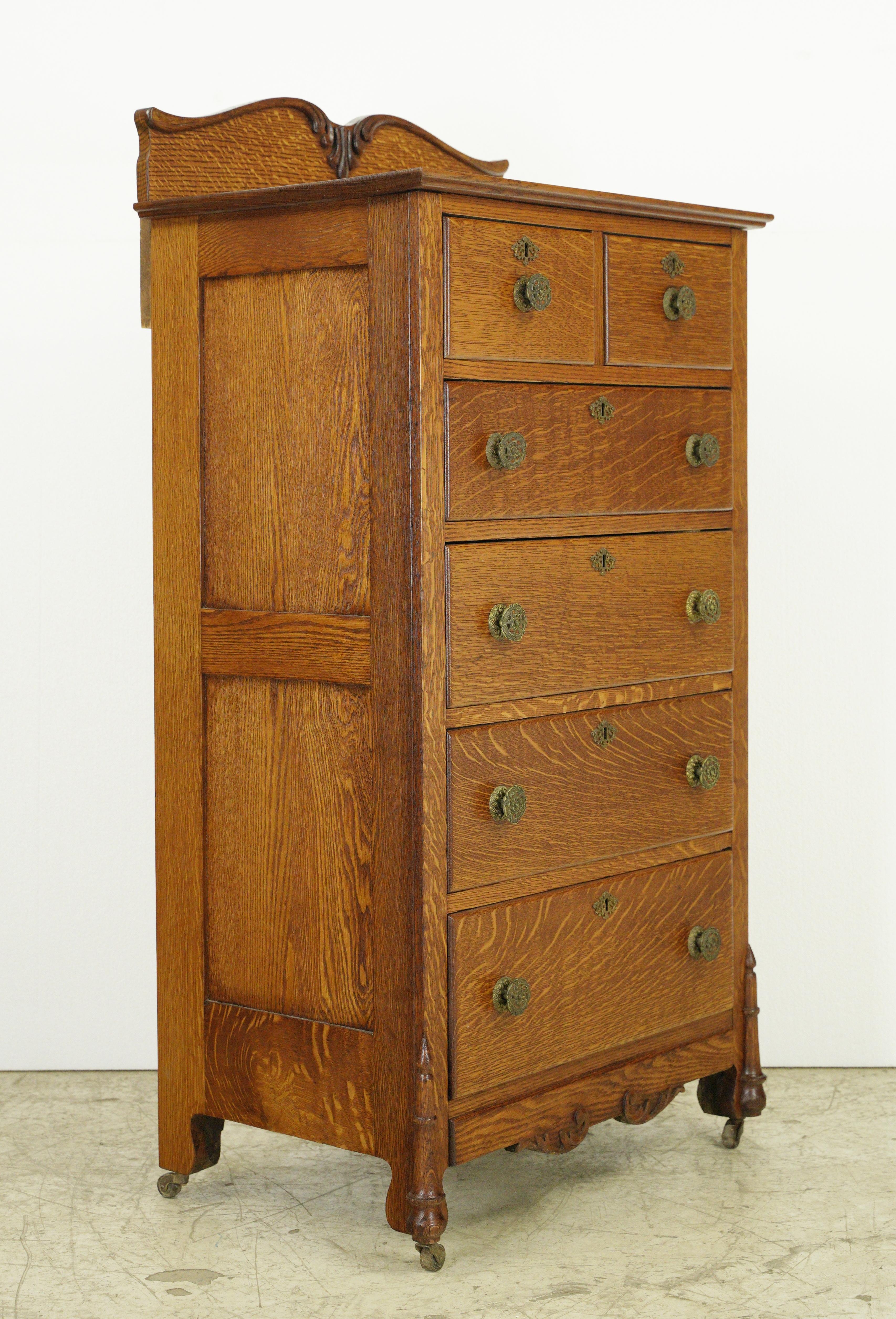 Refinished medium tone oak lingerie chest or high boy dresser with six dovetailed drawers, all original brass hardware and casters. Great details at feet and on back splash. One available. Please note, this item is located in one of our NYC