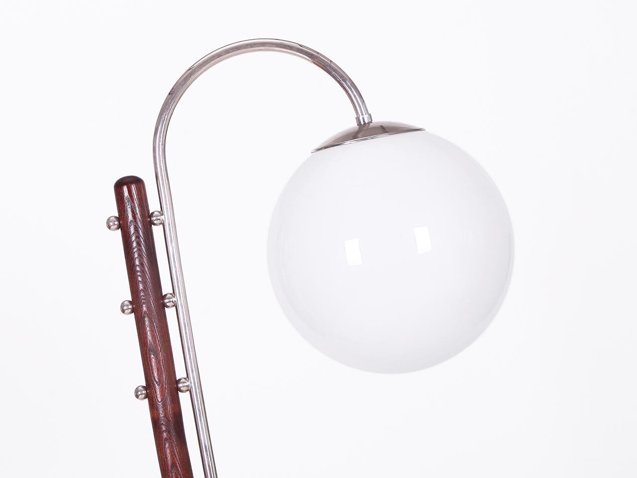 Rara lámpara de pie de Jindřich Halabala
Un modelo icónico de J. Halabala, diseñado en la década de 1930.
Esta lámpara combina madera teñida de oscuro con un globo de cristal opalino y tubos de acero cromado. 
Una obra maestra estilística que