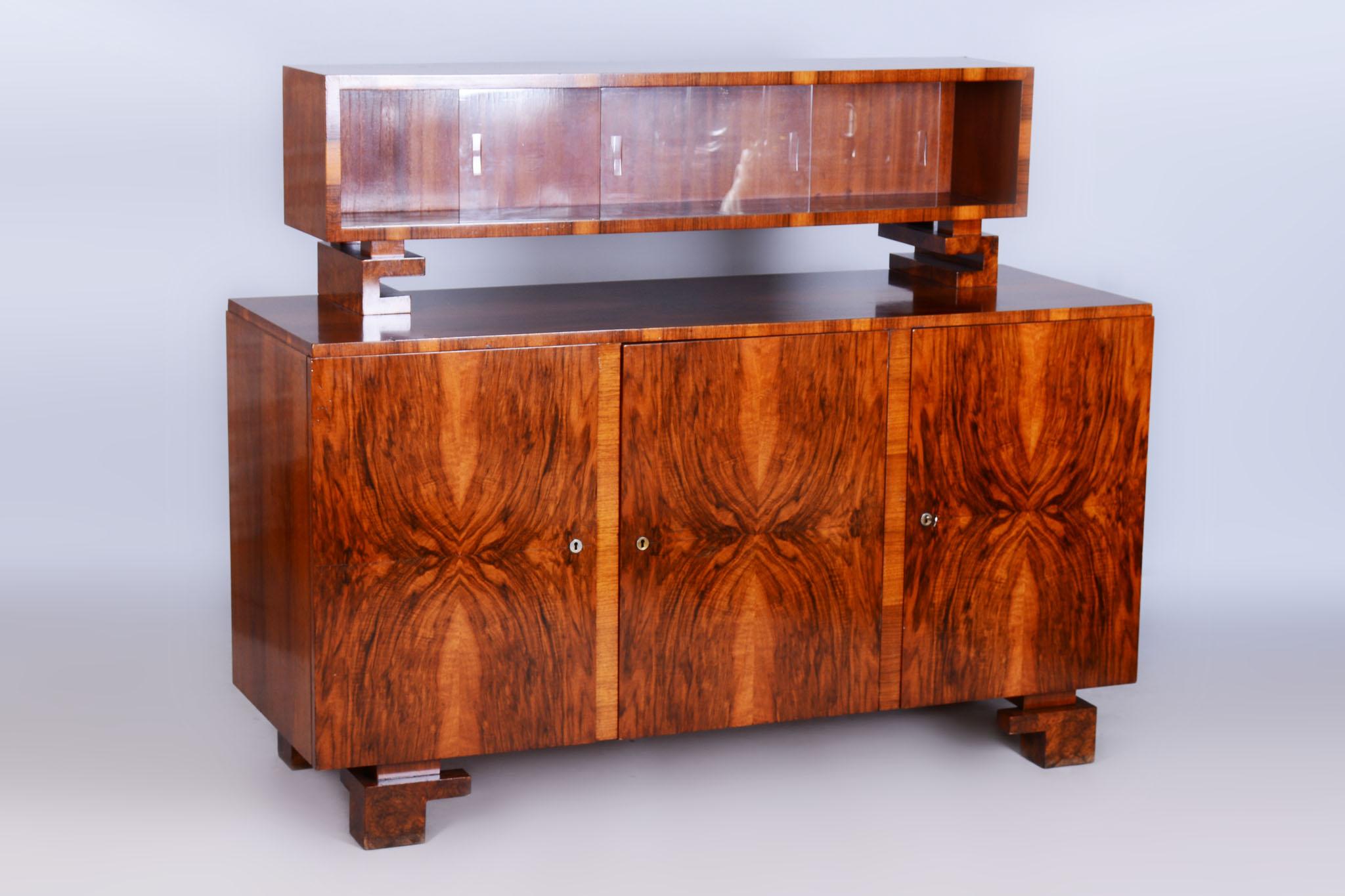 Dieses elegante Art-Déco-Sideboard aus dem frühen 20. Jahrhundert ist ein beeindruckendes Beispiel für tschechoslowakisches Design aus dieser Zeit. Aus Holz gefertigt und mit Nussbaumfurnier verziert, zeichnet er sich durch präzise Handwerkskunst