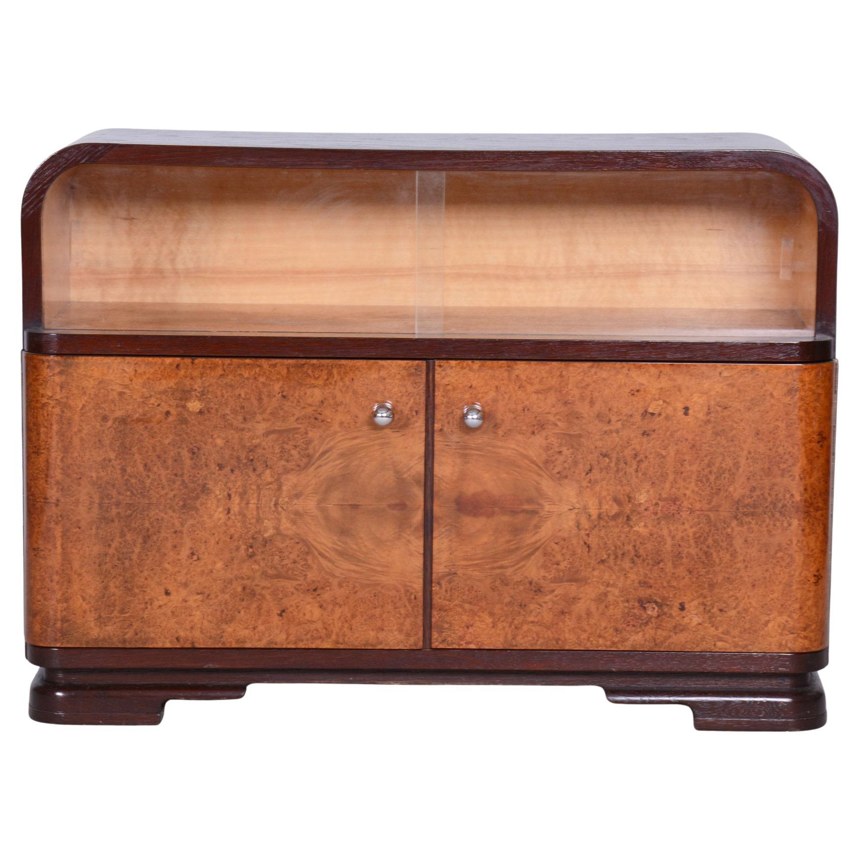 This cabinet from the 1930s is a stunning example of Czechoslovak Art Deco, blending elegance with functionality. Its surface features a combination of classic oak veneer and striking maple burl, giving it a unique and luxurious appearance.

The