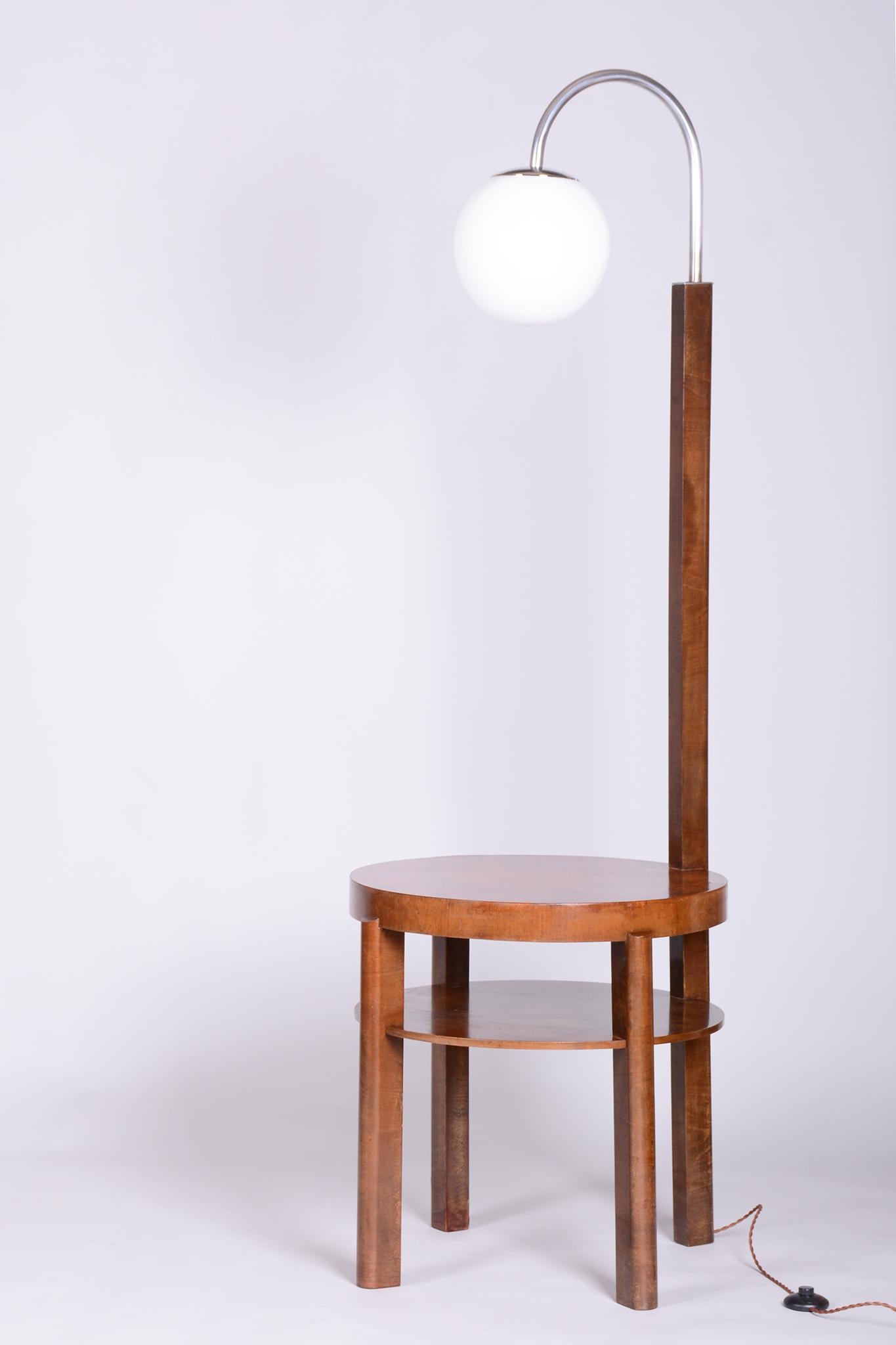 Cet élégant lampadaire Art déco provient de la Tchécoslovaquie des années 1930. Son design associe les tons chauds du bois à l'élégance froide du chrome, typique de ce style fonctionnaliste transitionnel.

La lampe est fabriquée en bois de hêtre