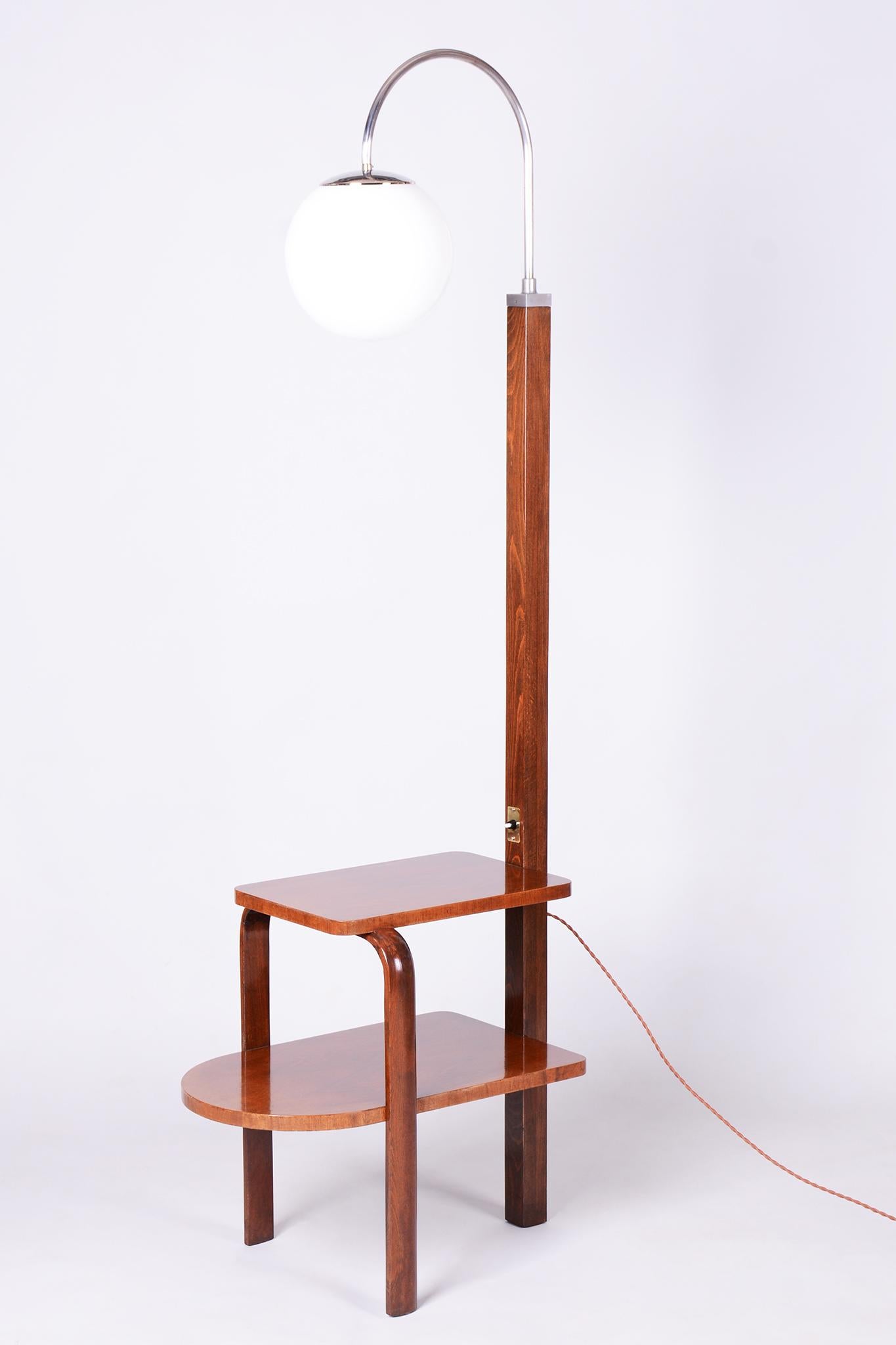 Questa elegante lampada da terra Art Déco proviene dalla Cecoslovacchia della prima metà del XX secolo ed è stata prodotta dalla rinomata azienda Thonet.

La lampada è realizzata con una combinazione di legno massiccio di faggio, impiallacciatura di