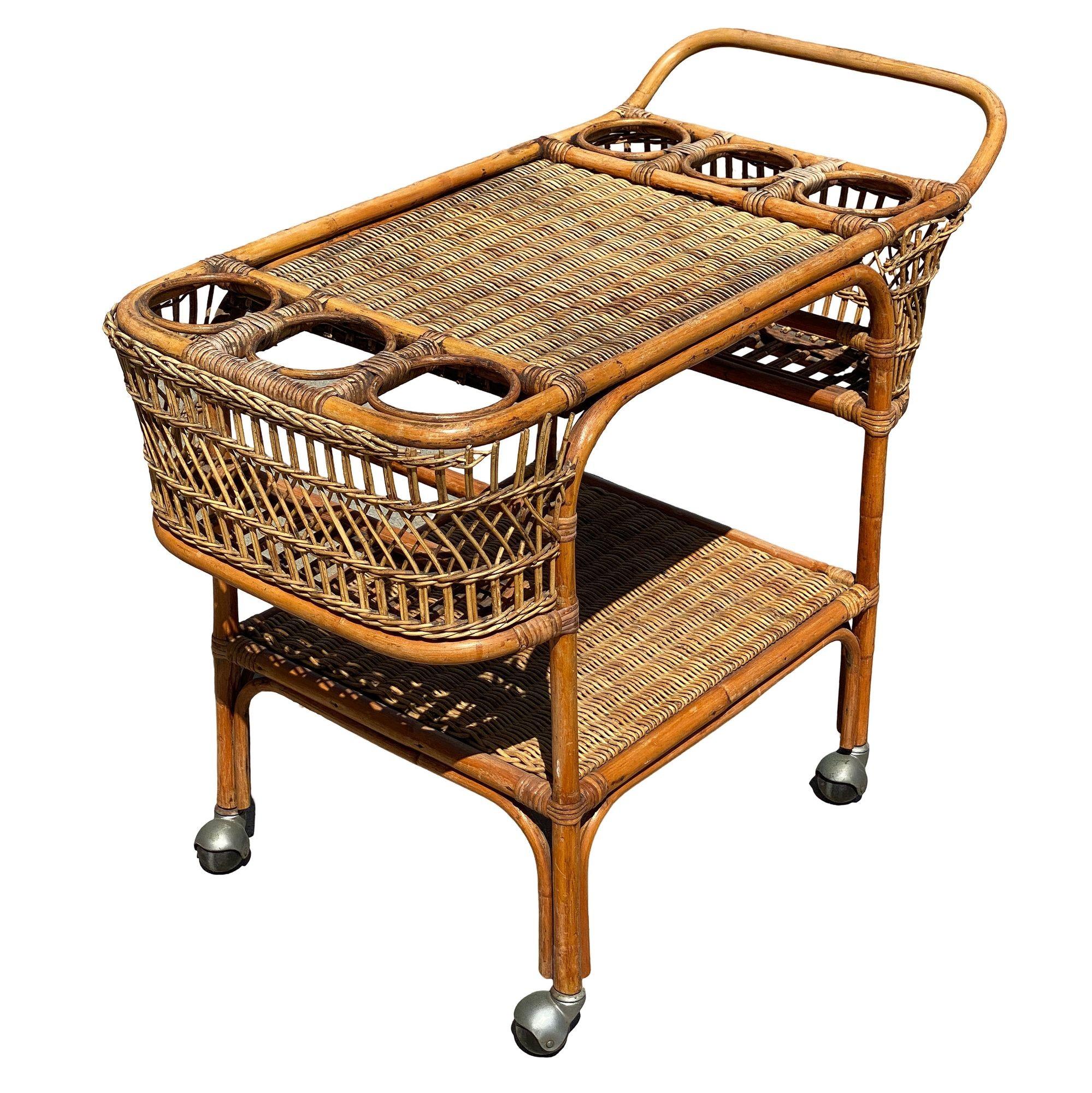 Questo carrello da bar in rattan di ispirazione Paul Frankl, splendidamente restaurato, presenta una struttura in rattan Pole Rattan con piani in vimini intrecciati e portabottiglie in rattan a bastoncino. Il carrello bar è dotato di due ripiani a