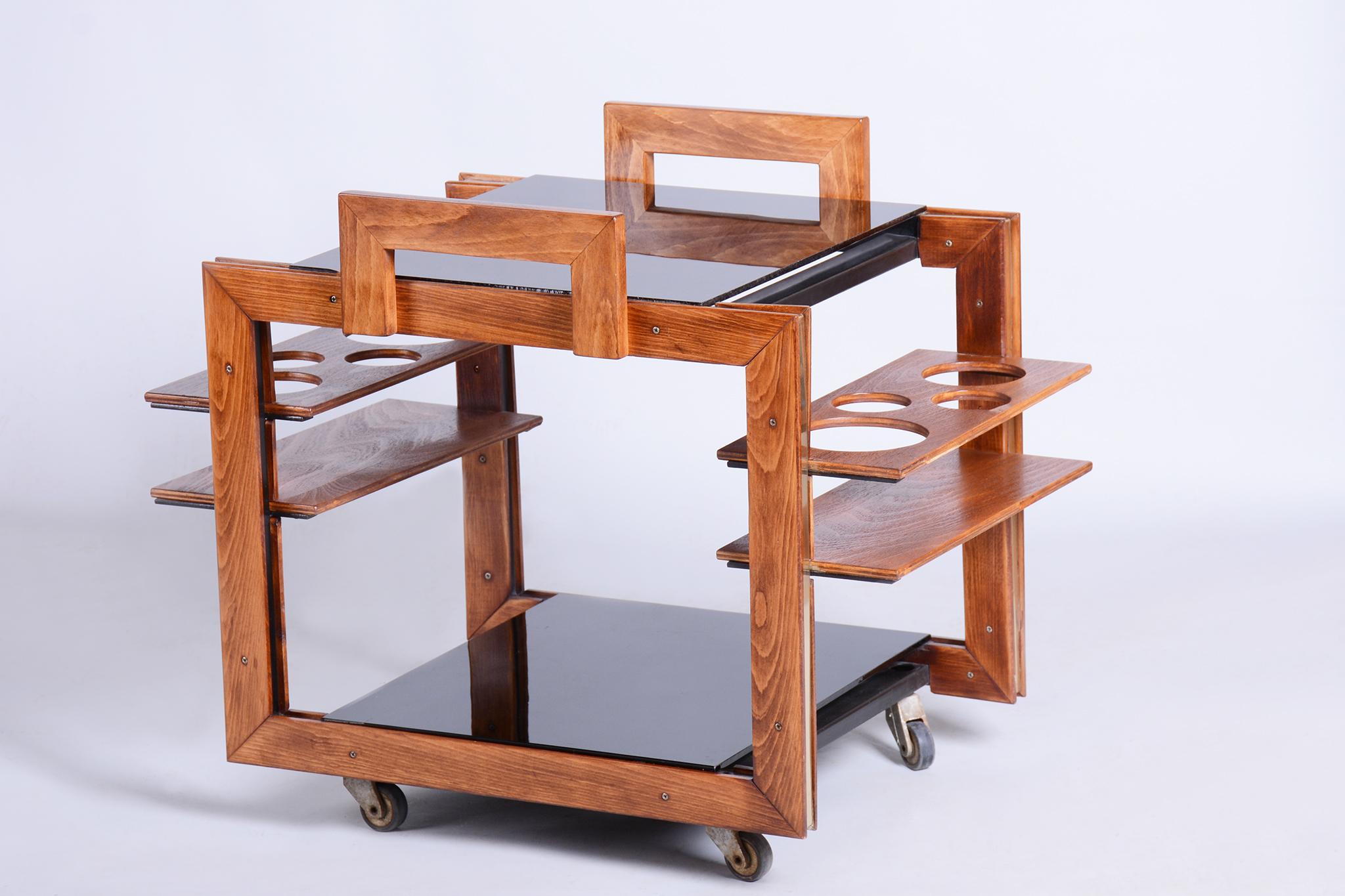 Questo elegante carrello da portata in stile Art Déco proviene dalla Cecoslovacchia e risale alla metà del XX secolo. È realizzato in legno di faggio e impreziosito da vetro opaxite nero e dettagli in ottone. Il carrello è stato sottoposto a un