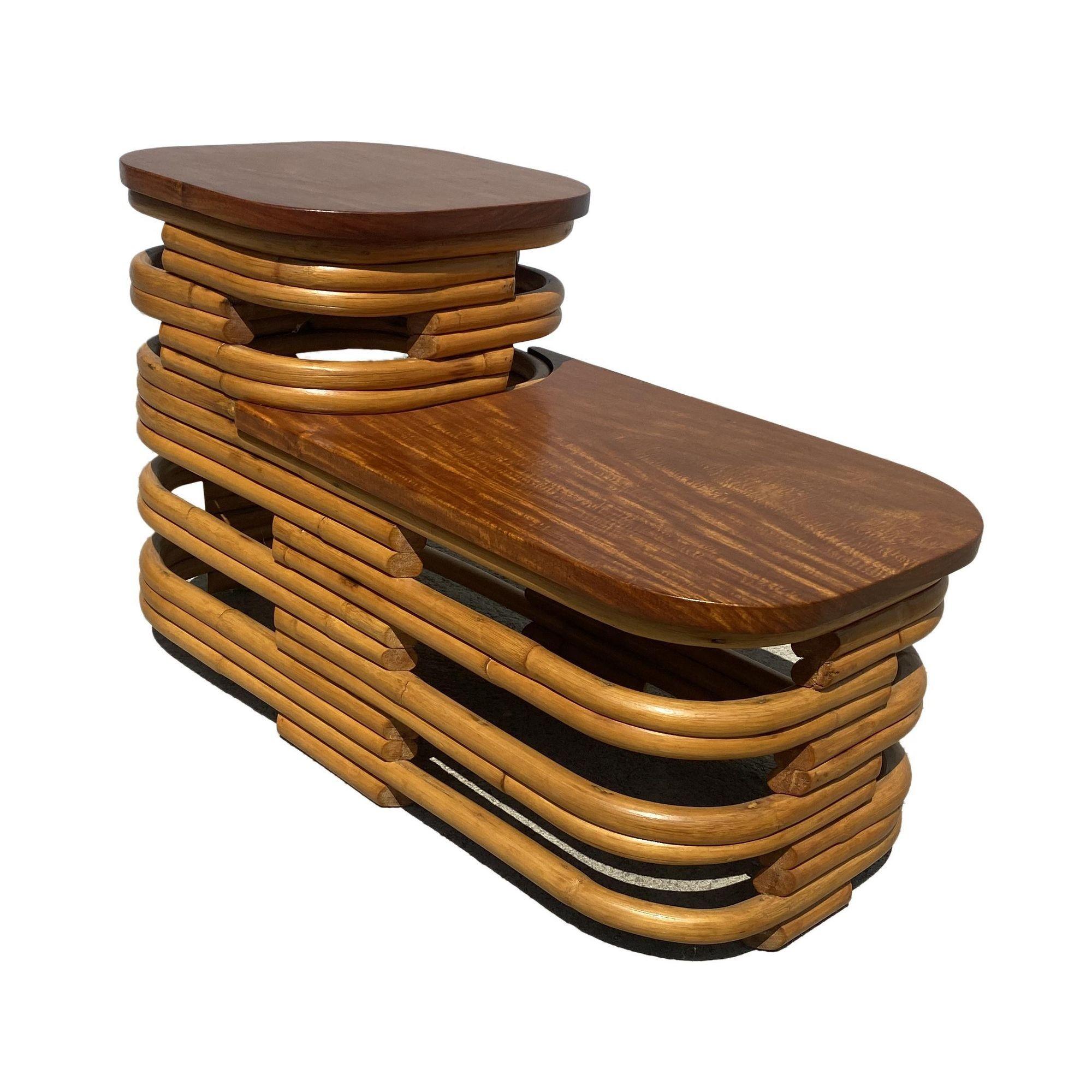 This beautifully restored pair of Paul Frankl style two-tier stacked rattan end lamp tables with cut-out sides and dark stained mahogany wood tops, all meticulously refinished to highlight the natural rattan’s warmth and durability. It is perfect