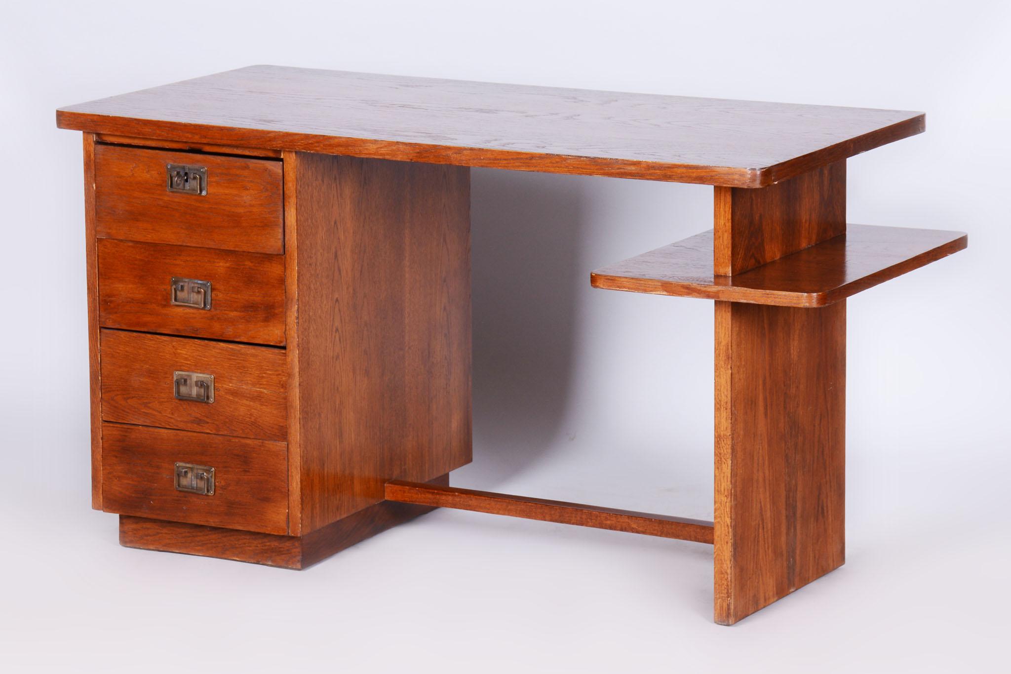 Este elegante escritorio, diseñado en estilo Art Déco, procede de la Checoslovaquia de la primera mitad del siglo XX. Fabricado con tablero de bloque chapado en roble y haya maciza, impresiona por su diseño atemporal y su precisa artesanía. Los