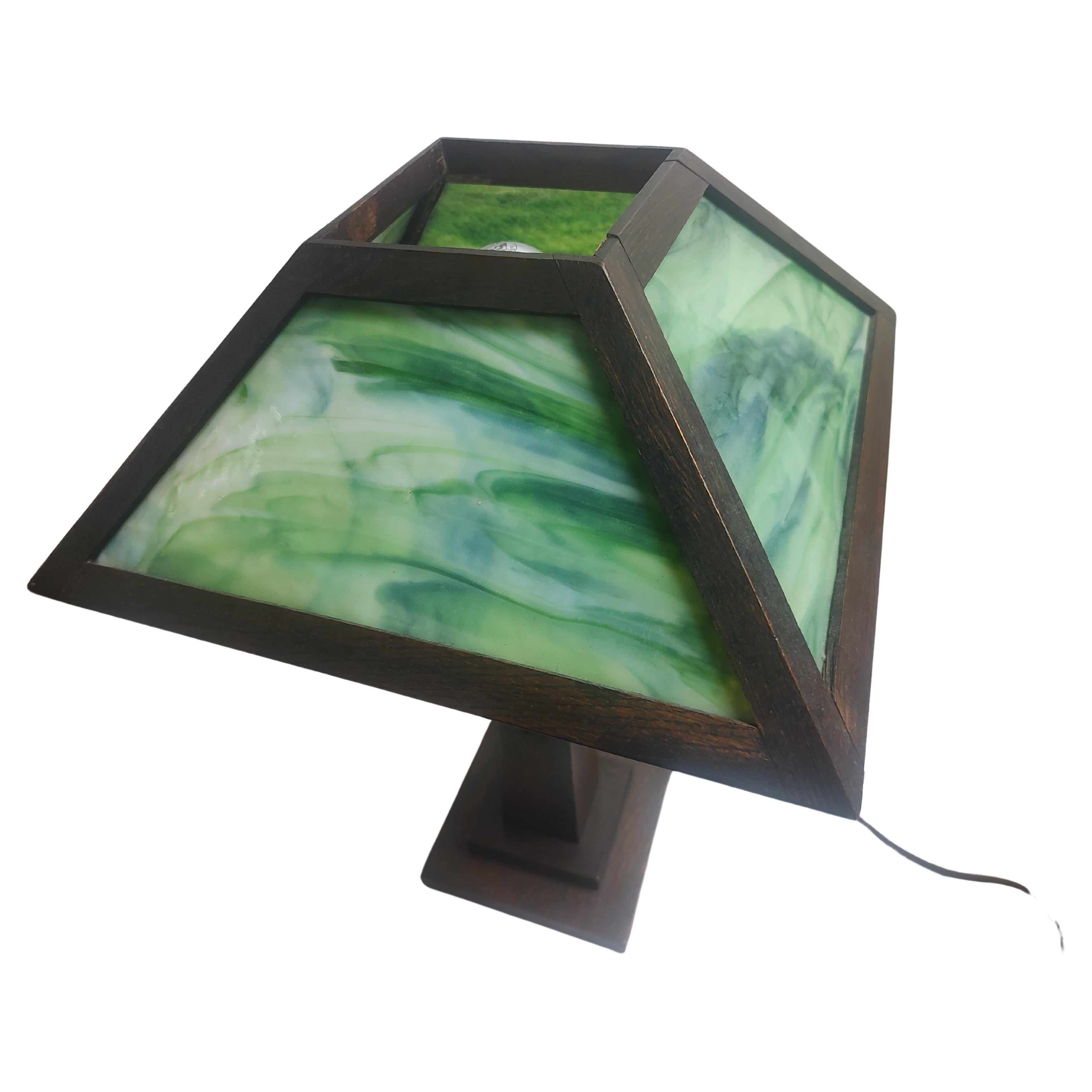 Espectacular y temprana versión de la lámpara de mesa Mission Arts & Crafts, era una lámpara de aceite y fue convertida profesionalmente a eléctrica con el máximo cuidado y respeto a la pieza. Precioso cristal de escoria verde y roble aserrado en